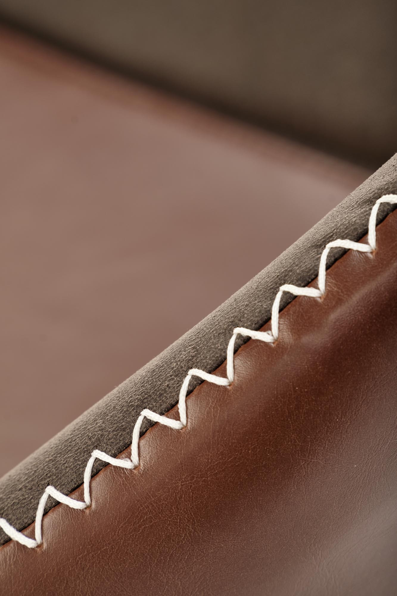 Zbliżenie na szwy ciemnoszarego krzesła K304 z brązową ekoskórą.
