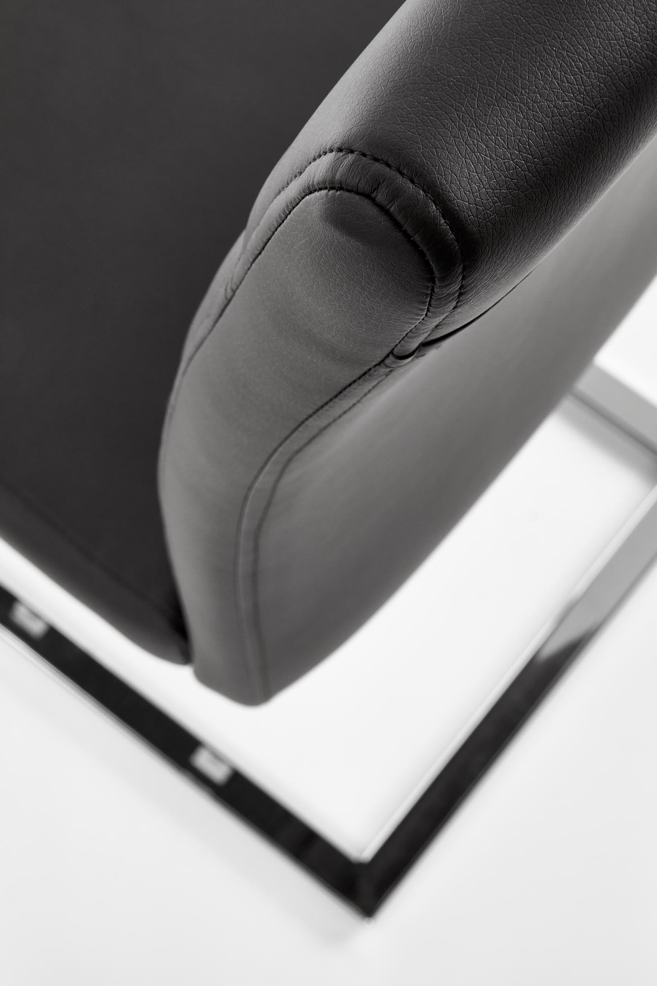 Zbliżenie na czarne krzesło K85 z eco skóry na chromowanych płozach.