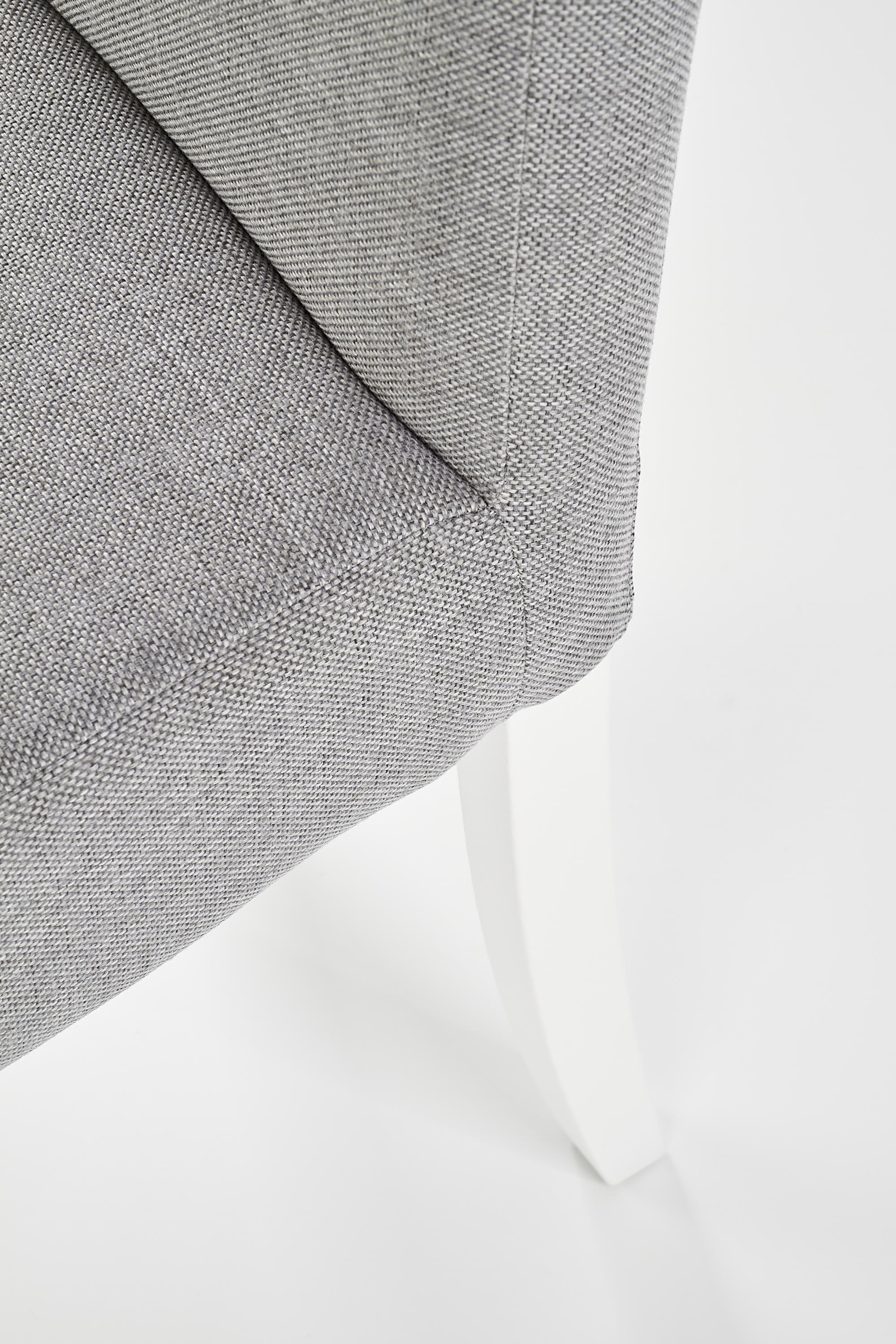 Zbliżenie na szare tapicerowane siedzisko krzesła CLARION z białymi drewnianymi nogami.