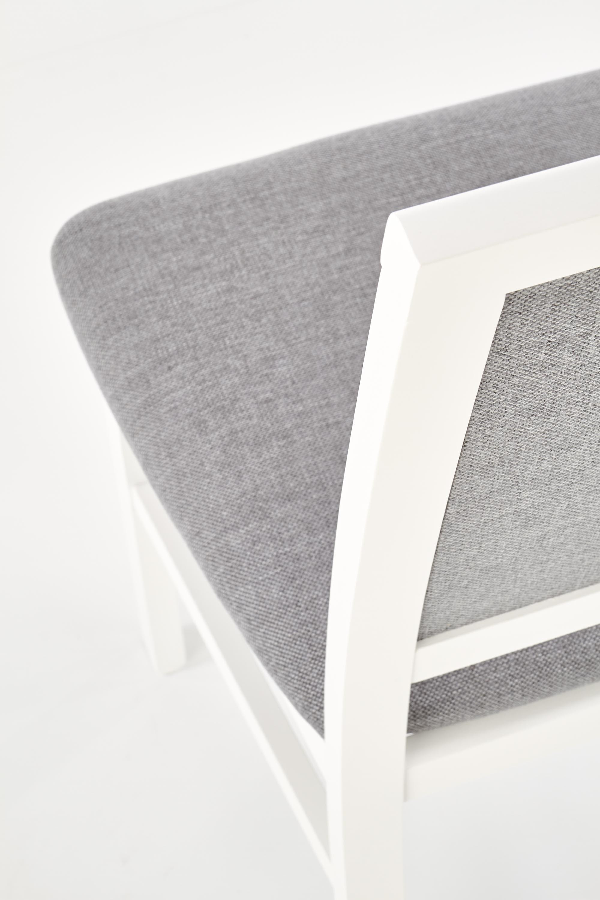 Zbliżenie na szare tapicerowane siedzisko i białą drewnianą ramę krzesła SYLWEK.