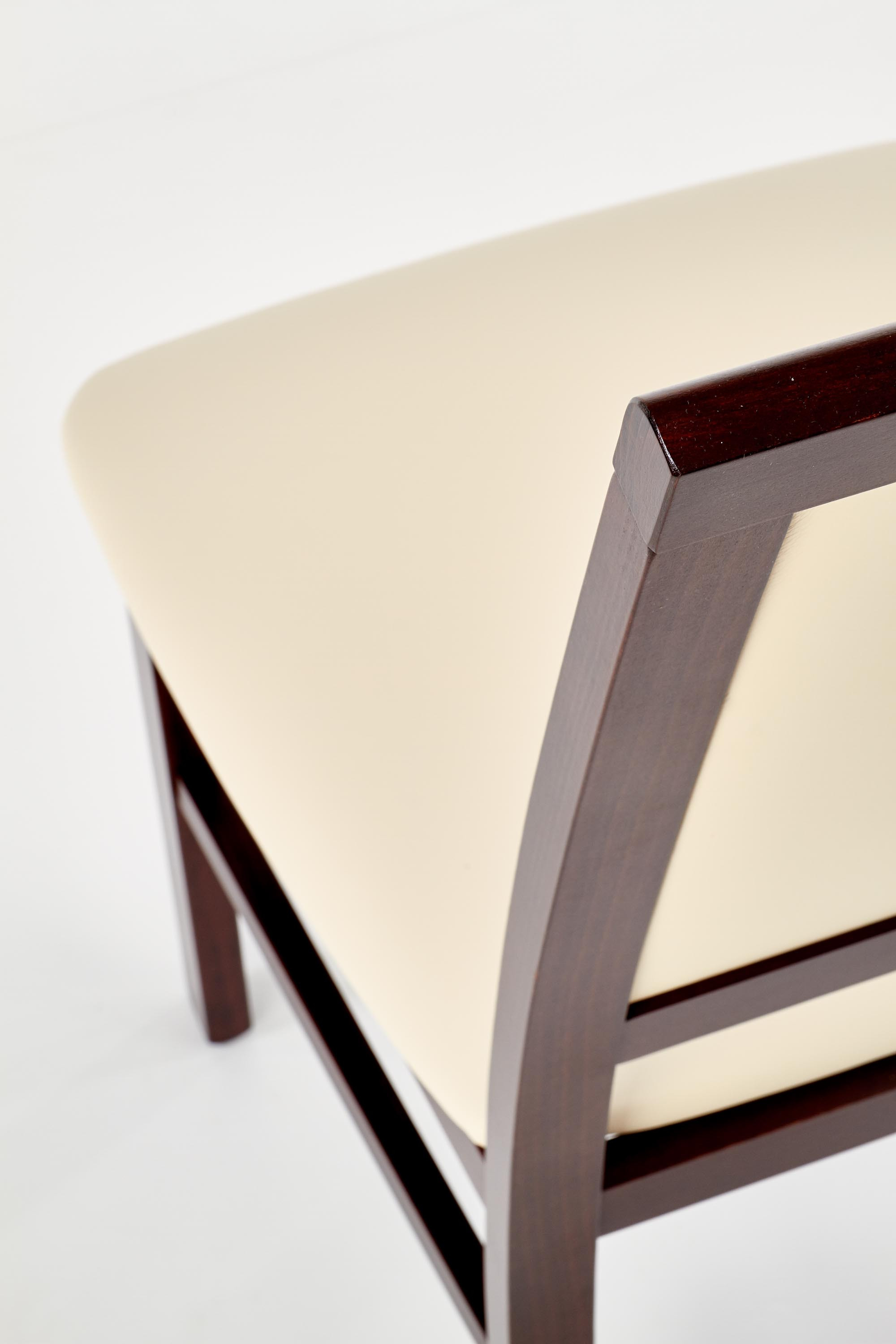 Zbliżenie na beżowe tapicerowane siedzenie i ciemne drewniane oparcie krzesła SYLWEK 1.