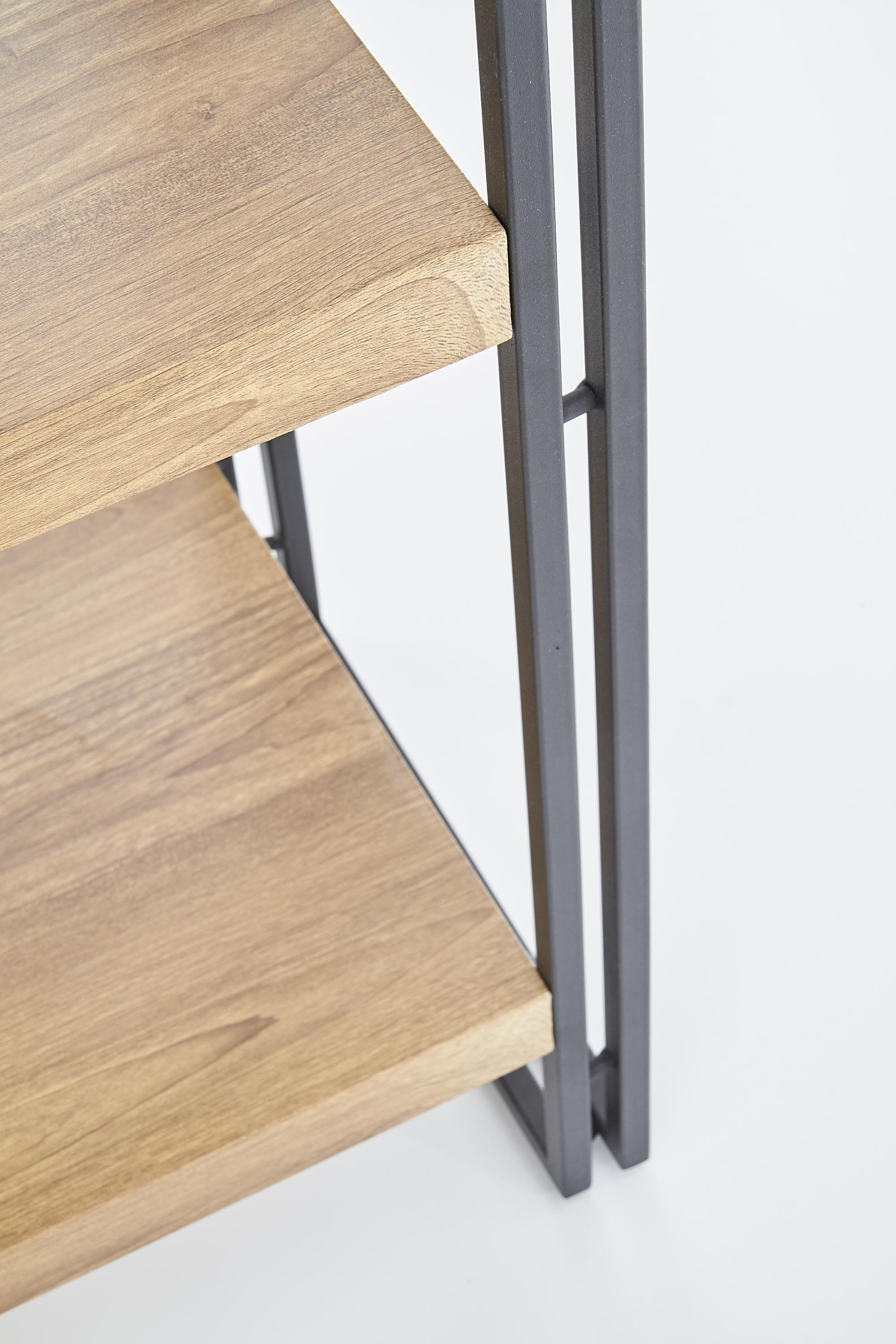 Zbliżenie na półki regału Bertoło w kolorze dąb złoty z czarną metalową ramą.