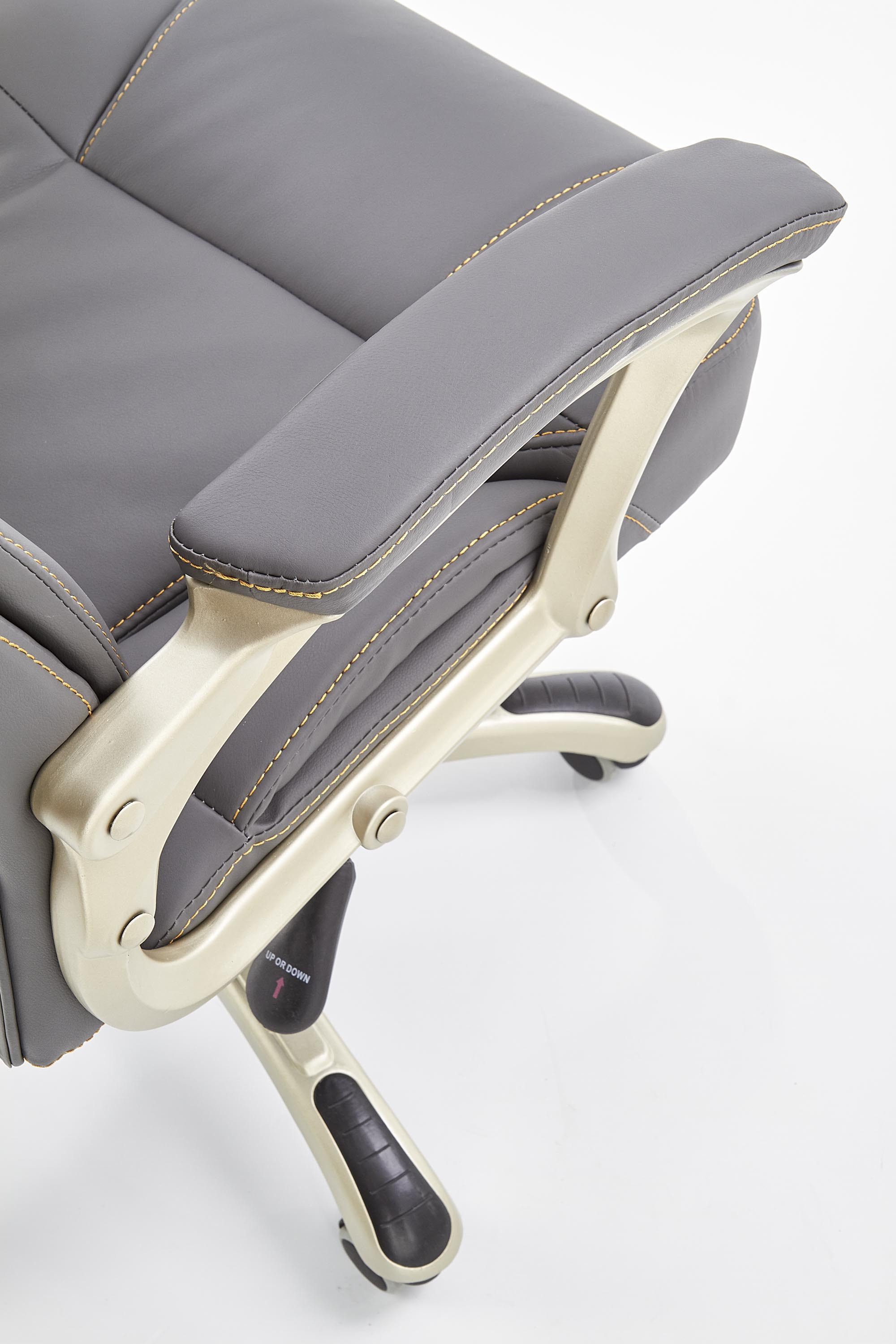 Zbliżenie na podłokietnik i siedzisko popielatego fotela gabinetowego DESMOND z eco skóry.