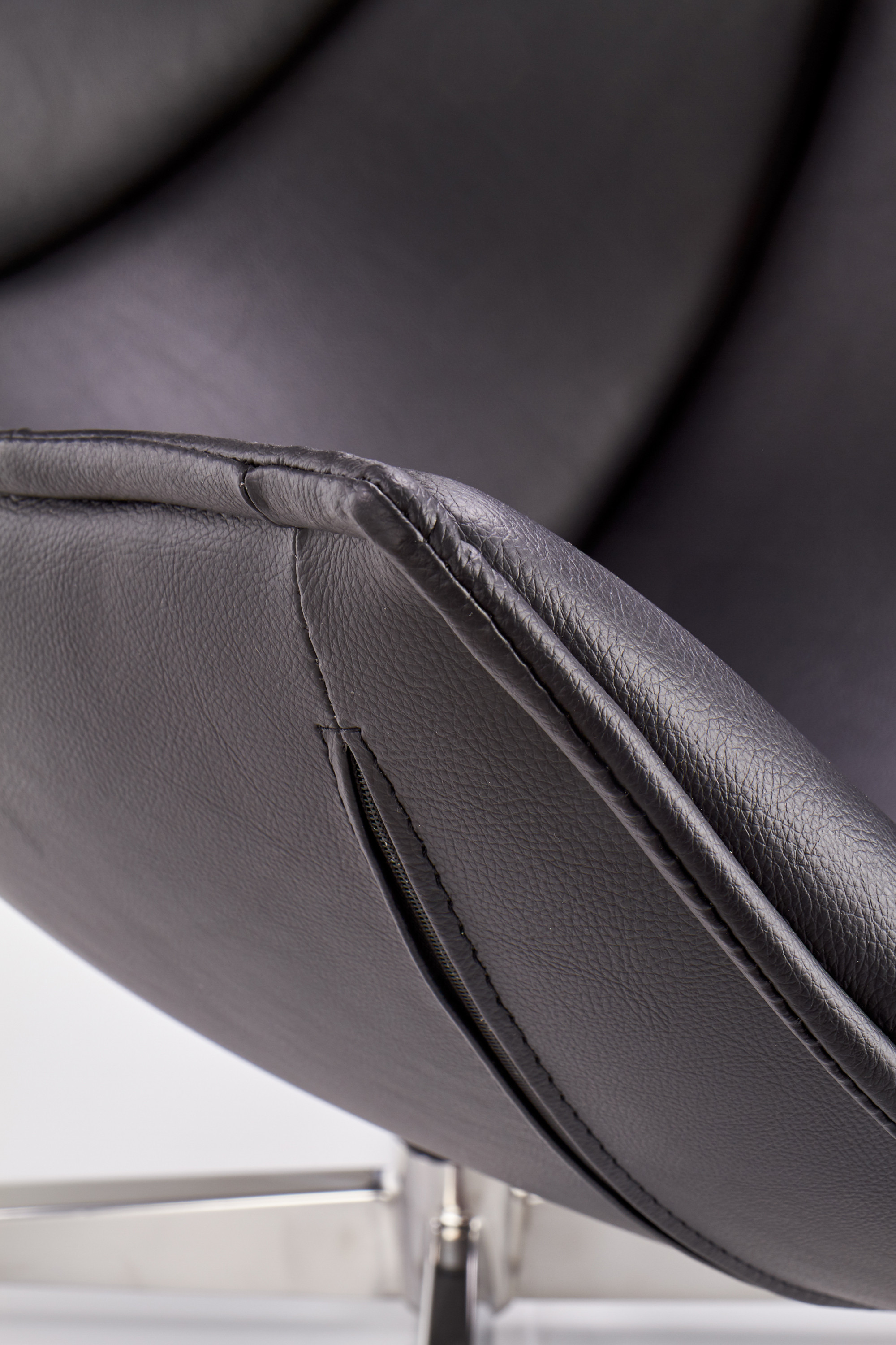 Zbliżenie na czarną eco skórę i stalową podstawę obrotowego fotela wypoczynkowego LUXOR.