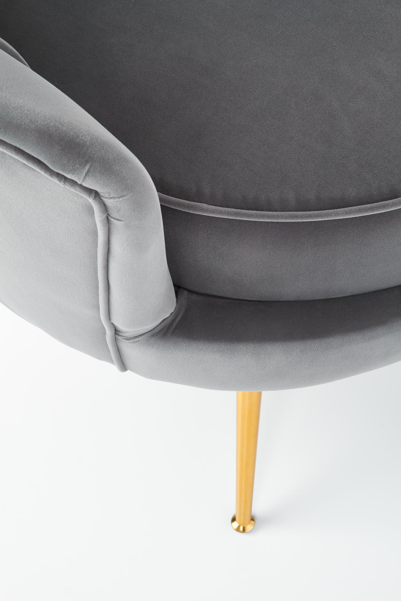 Zbliżenie na popielaty fotel AMORINITO z aksamitu na złotych nogach.