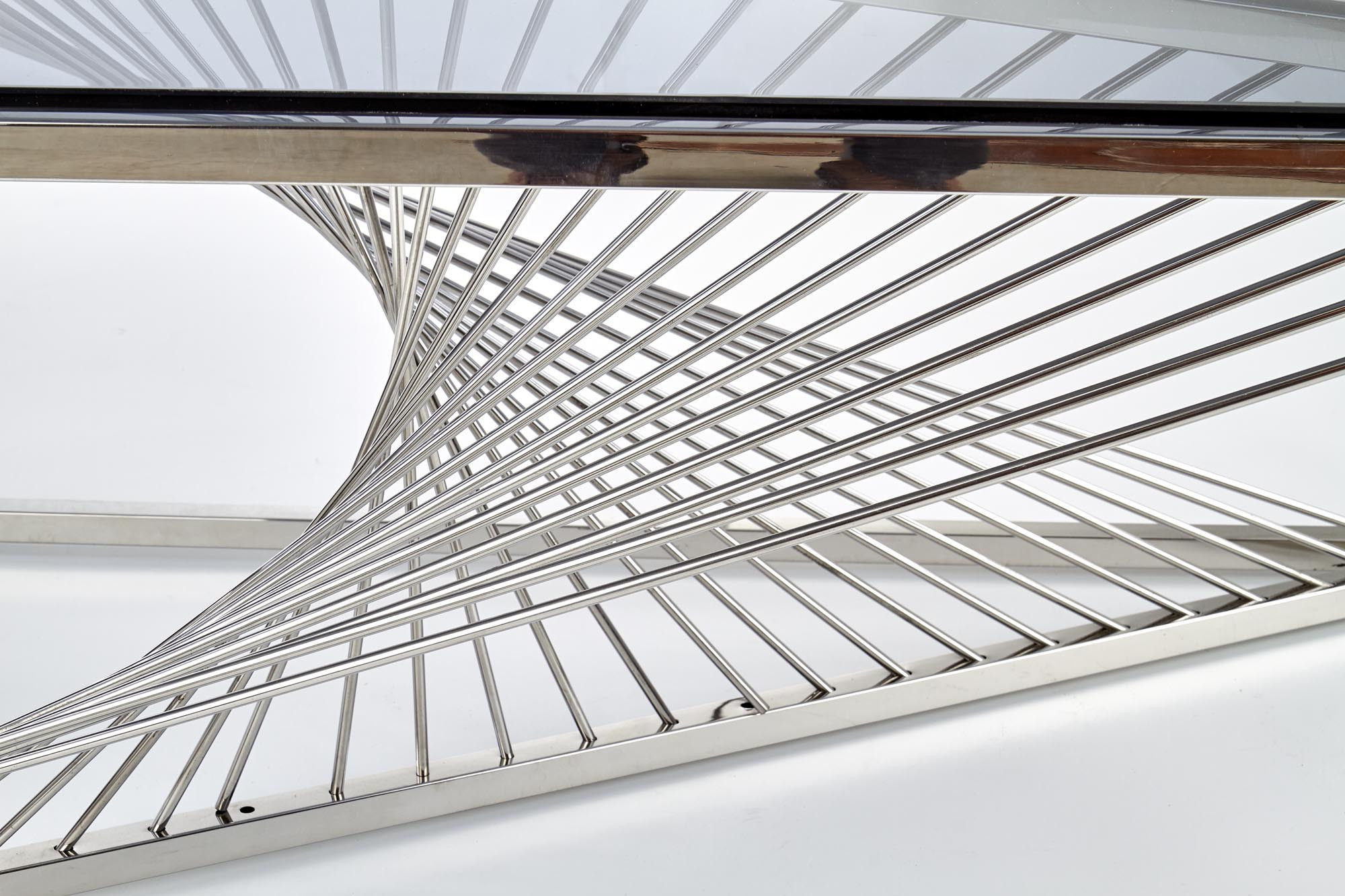 Zbliżenie na srebrny stelaż stolika kawowego INFINITY z dymionym szklanym blatem.