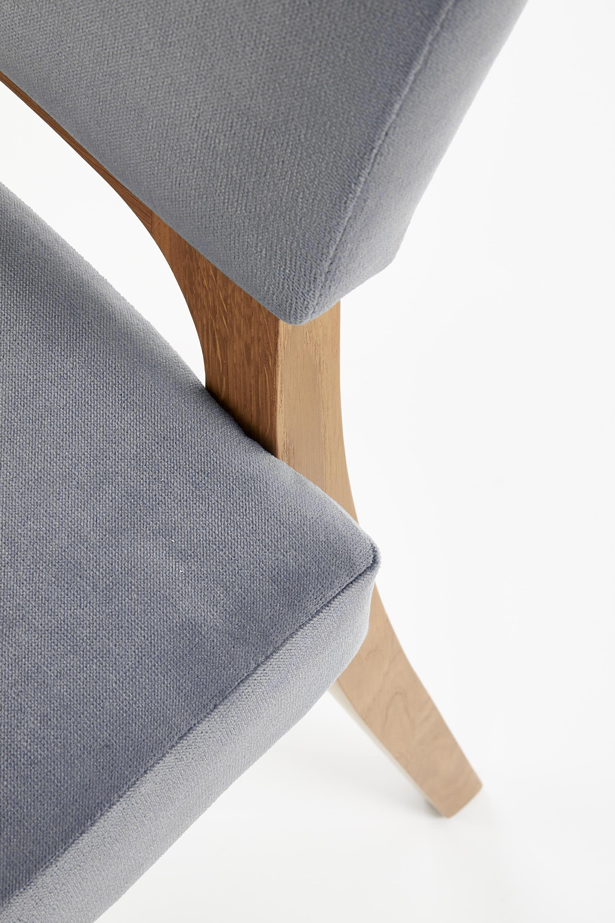 Zbliżenie na popielate drewniane krzesło WENANTY z tapicerowanym siedziskiem i oparciem.