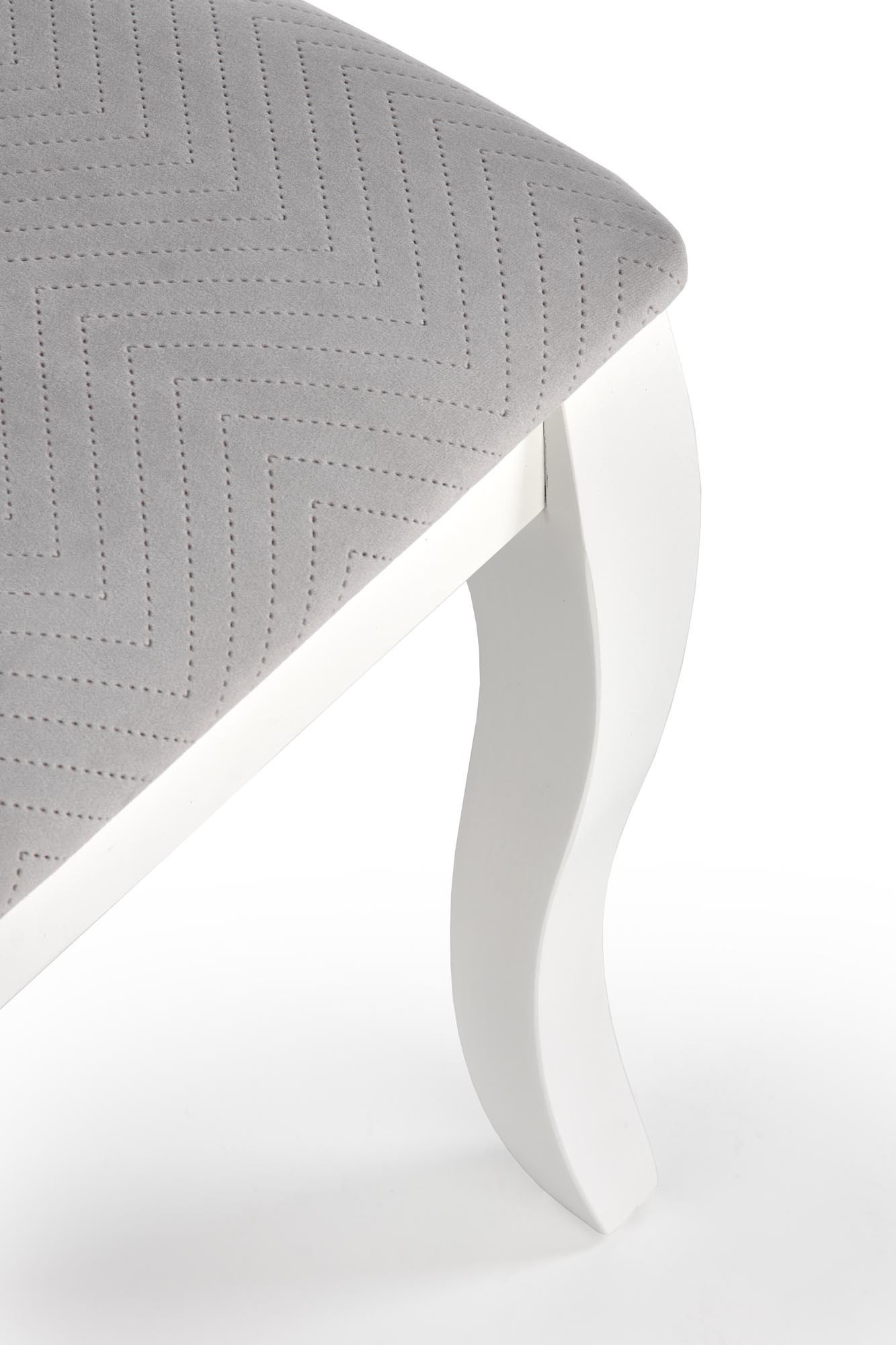 Zbliżenie na popielate siedzisko i białą drewnianą nogę krzesła VELO w stylu ludwikowskim.