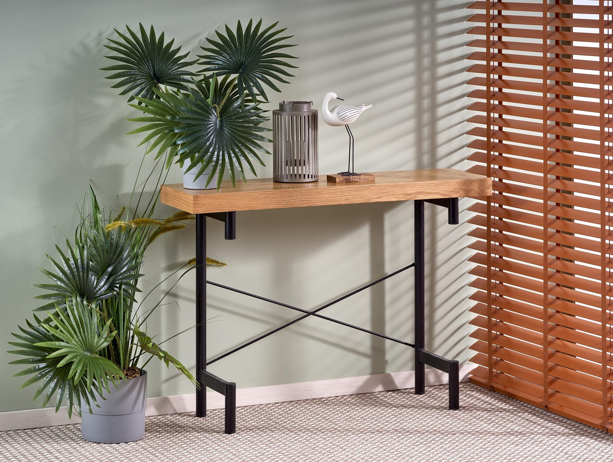 Przedni widok konsolki INFERNO z naturalnego dębu i czarnymi metalowymi nogami, obok roślin doniczkowych.