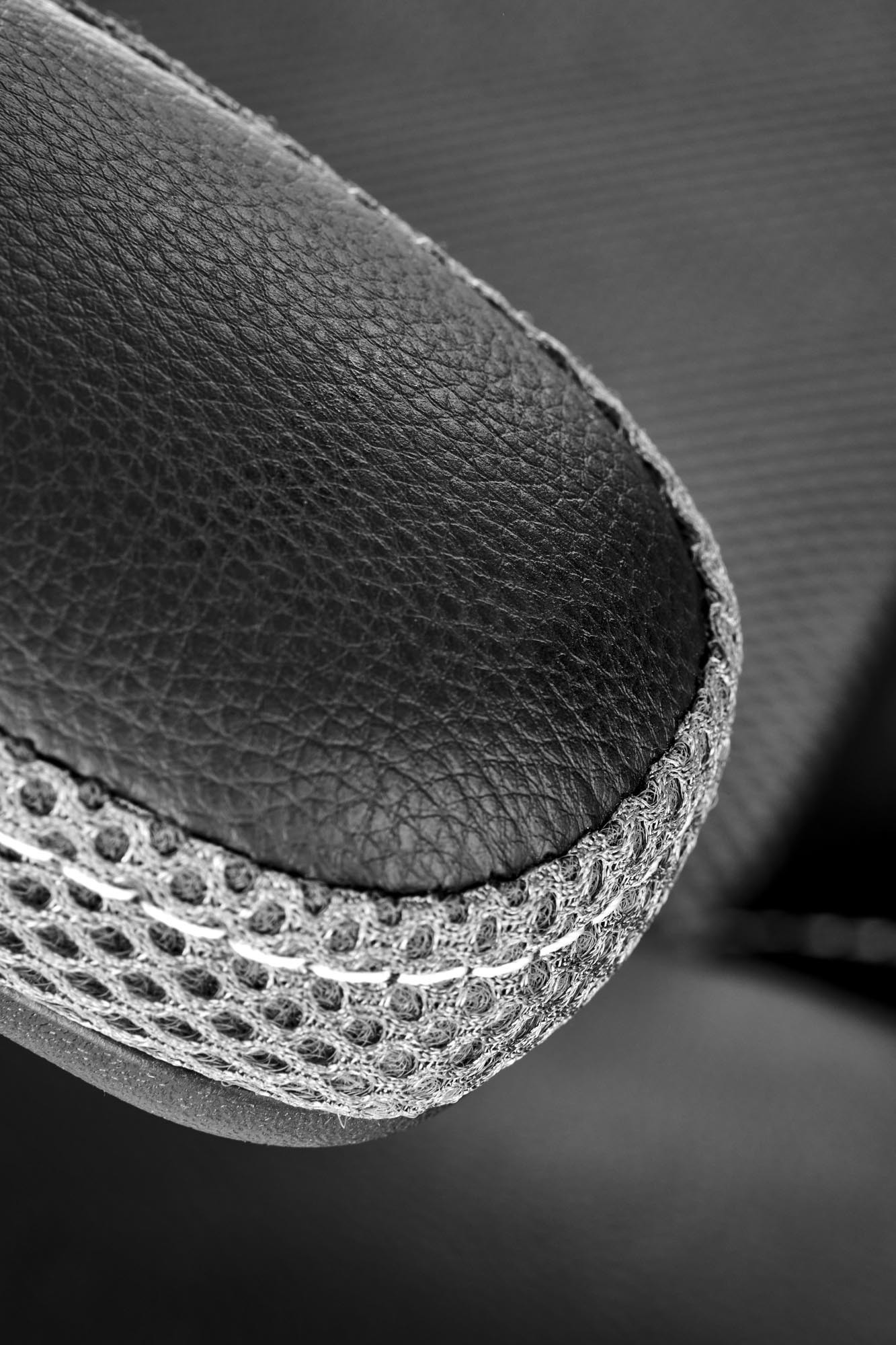 Zbliżenie na czarną skórzaną poduszkę fotela biurowego BERKEL z siatkowym wykończeniem.