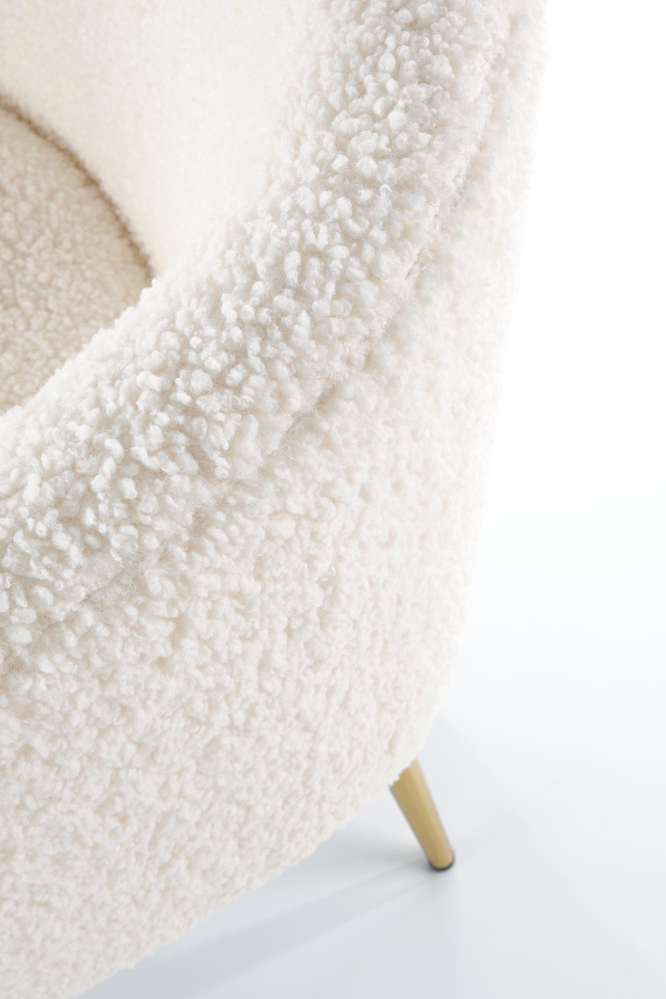 Zbliżenie na kremową tkaninę boucle i drewnianą nogę fotela GRIFON 2.