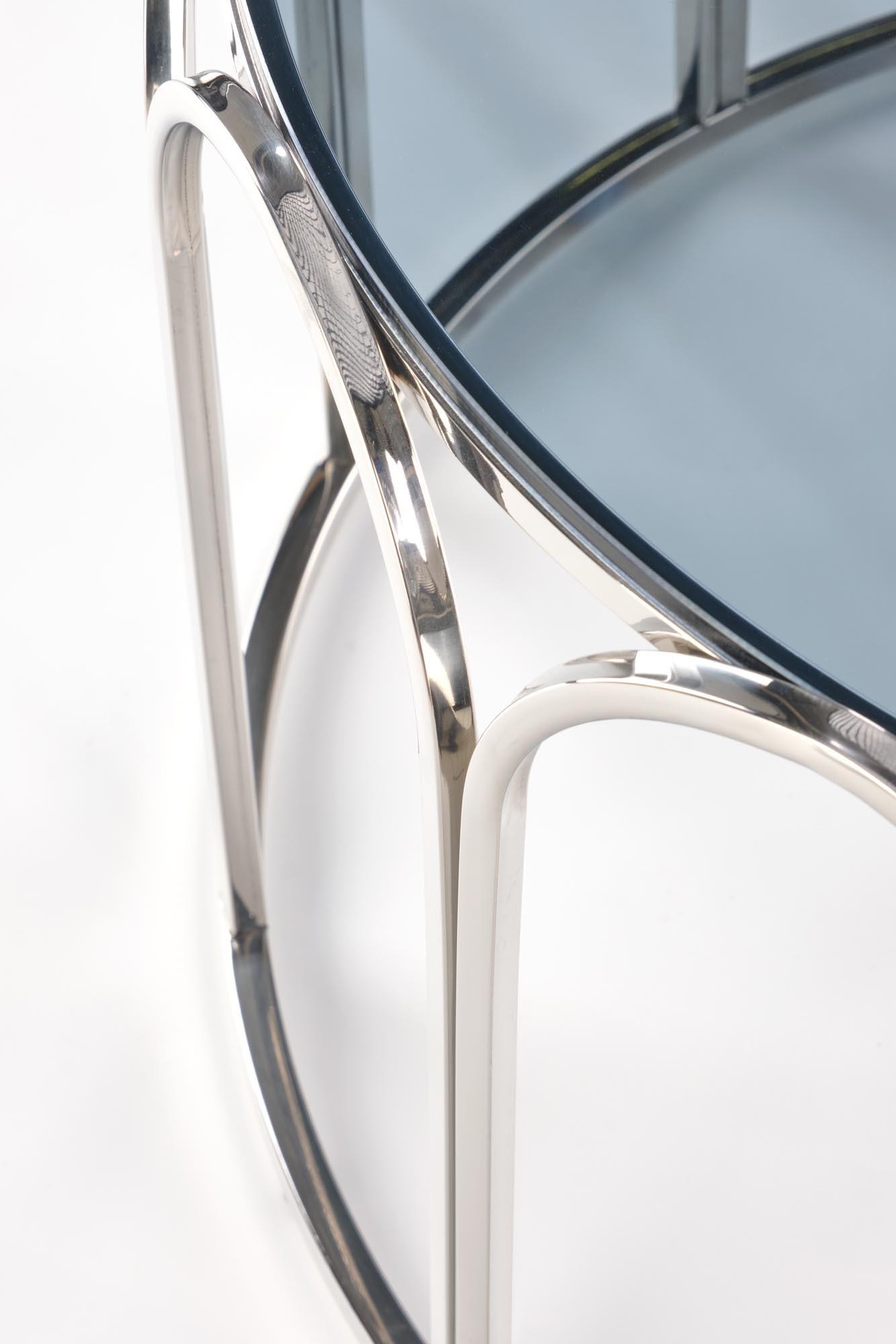 Zbliżenie na metalową podstawę i dymione szkło okrągłej ławy OLIVIA.