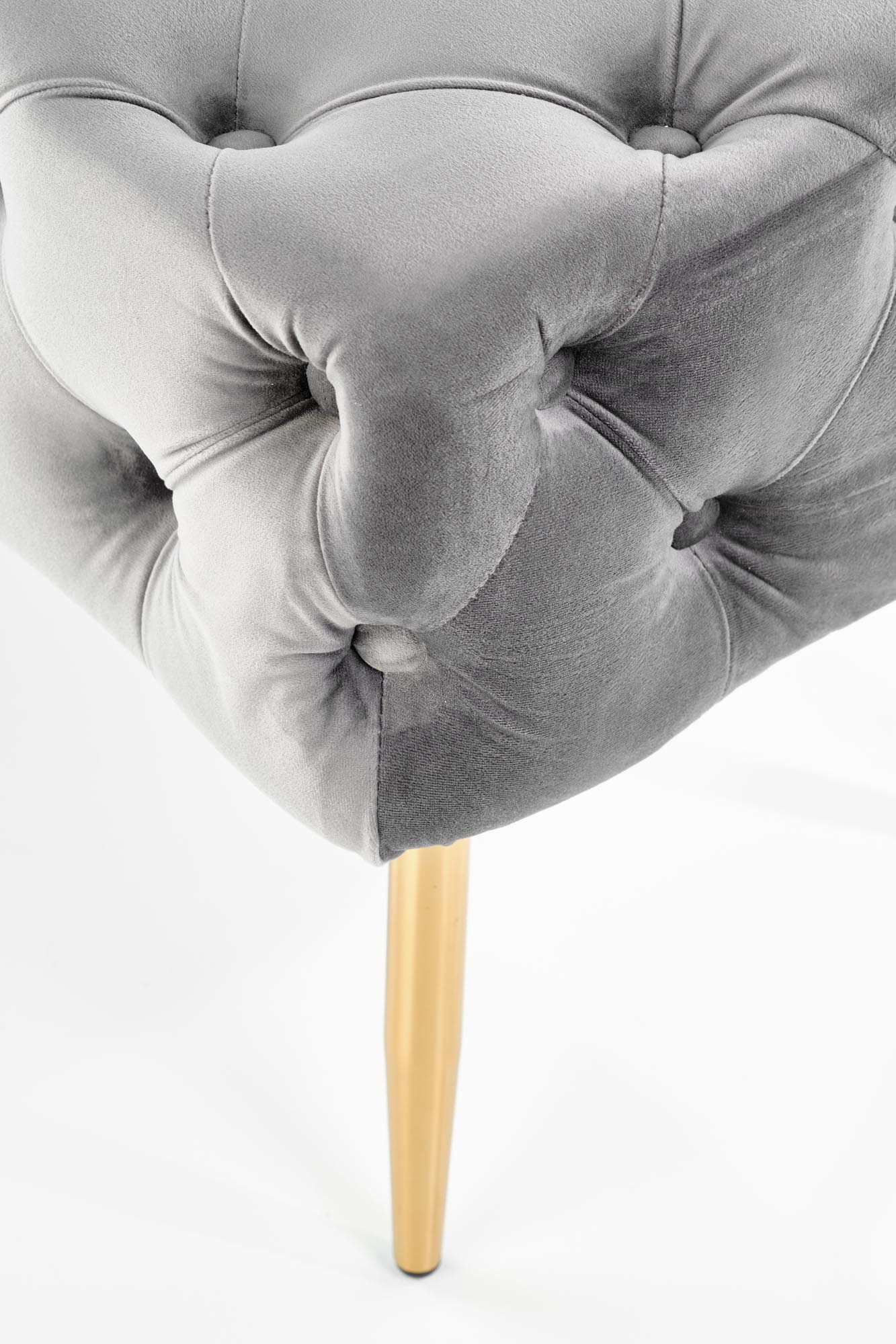 Zbliżenie na pikowane siedzisko szarej aksamitnej ławki ATHENA z złotą nogą.