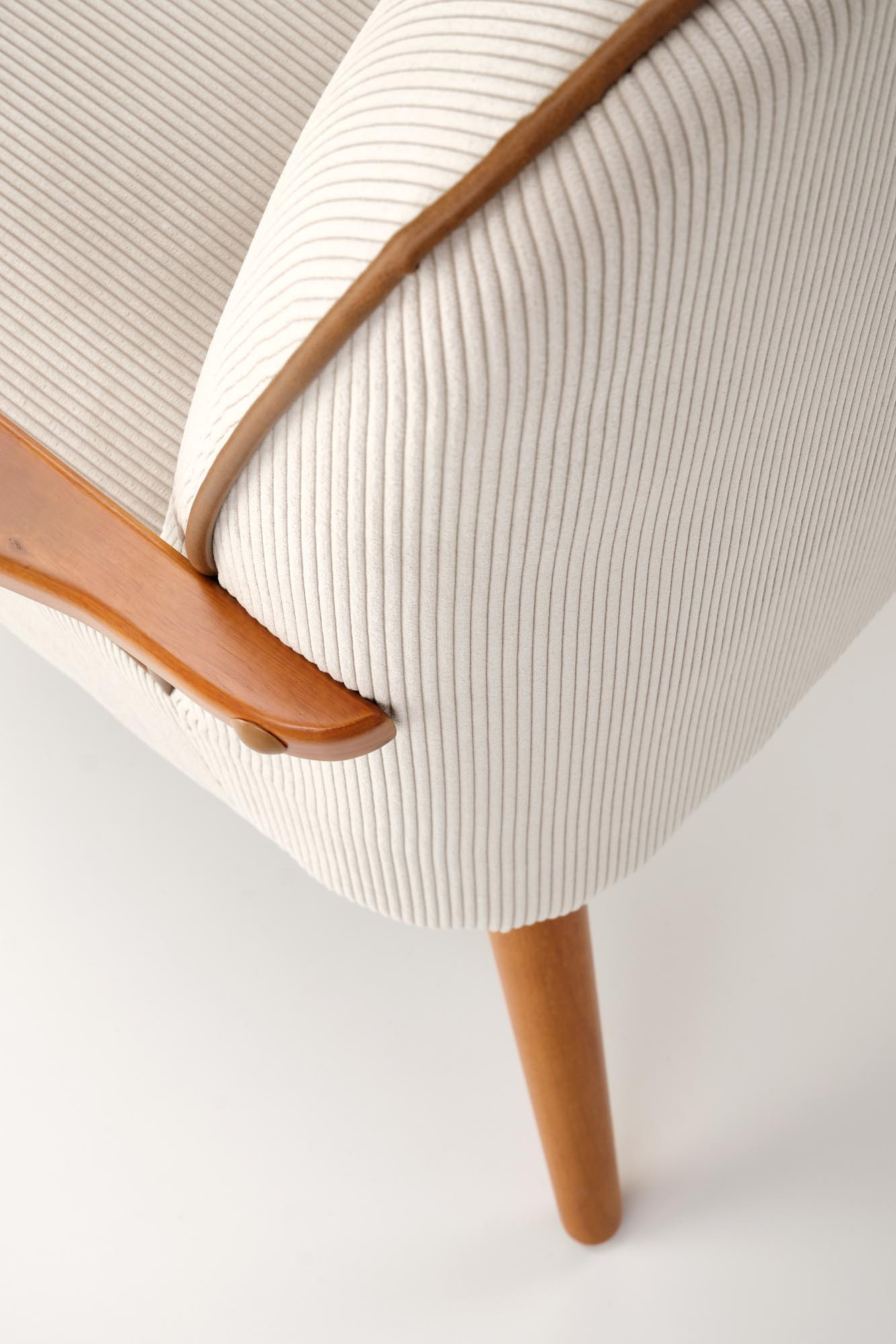 Zbliżenie na jasnobeżową tapicerkę i drewniane elementy fotela PASTORE.