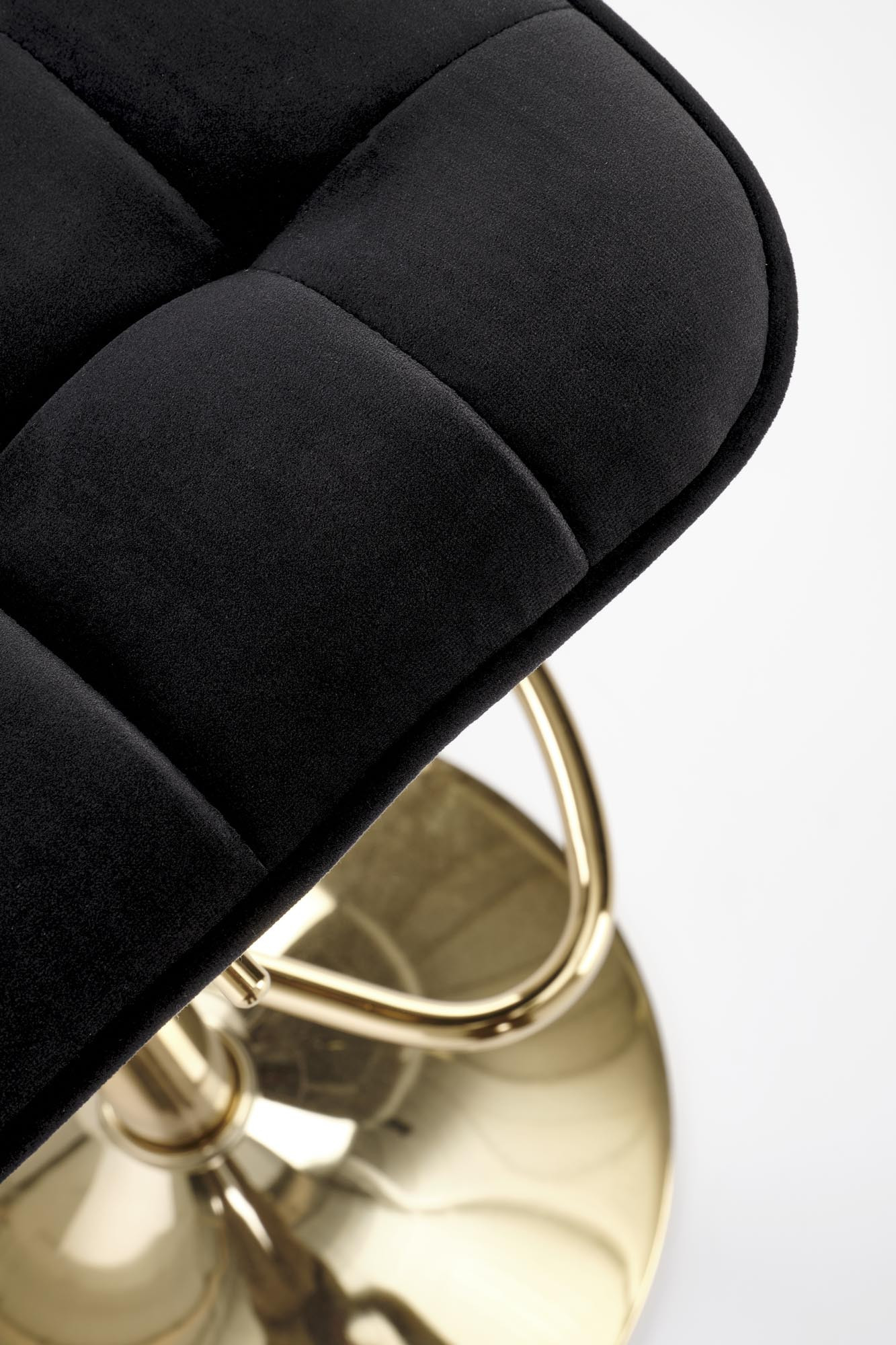 Zbliżenie na czarne pikowane siedzisko i złotą podstawę hokera H120.