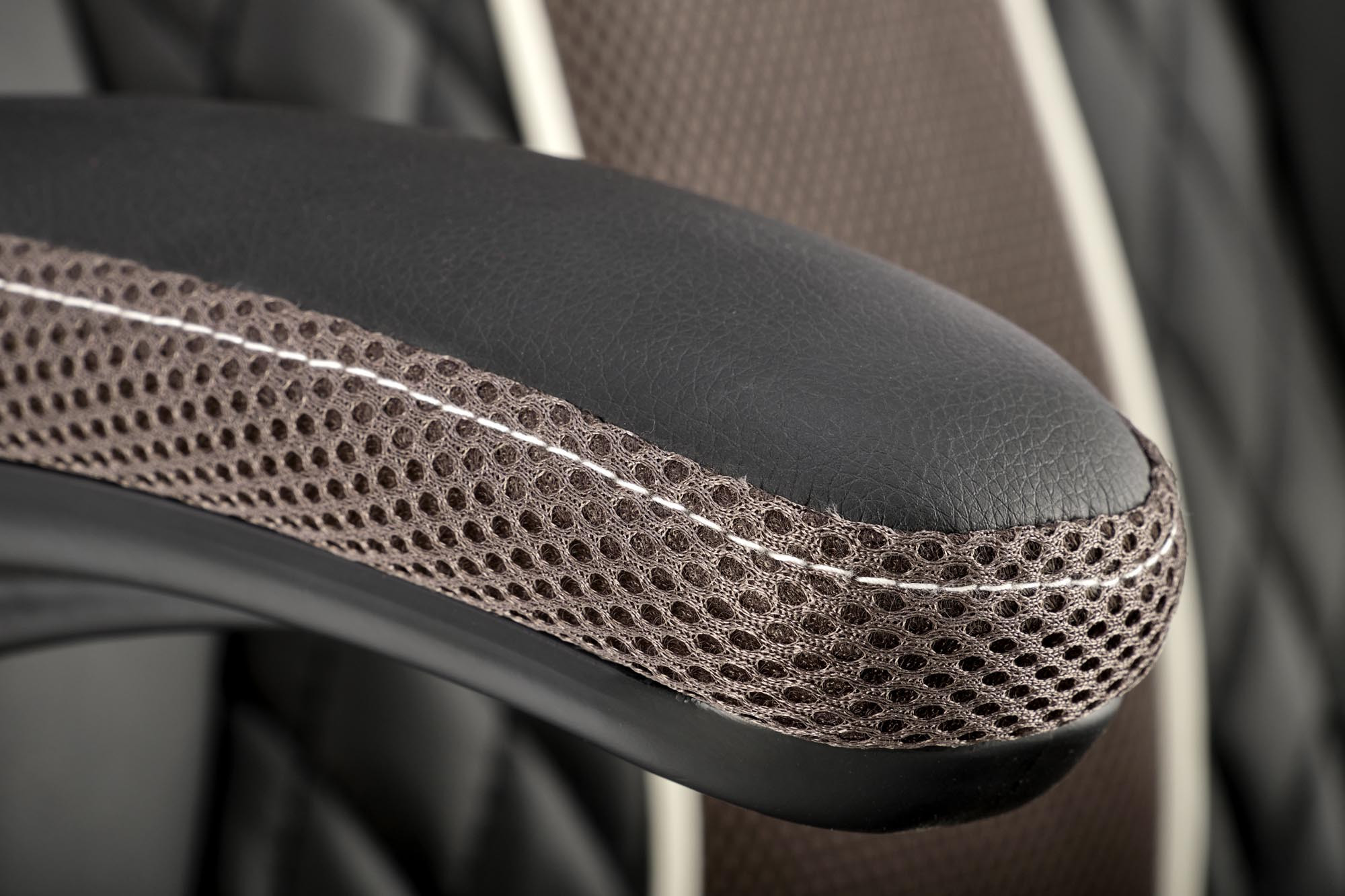 Zbliżenie na podłokietnik czarno-popielatego fotela HAMLET z eko skóry i siateczkowym wykończeniem.