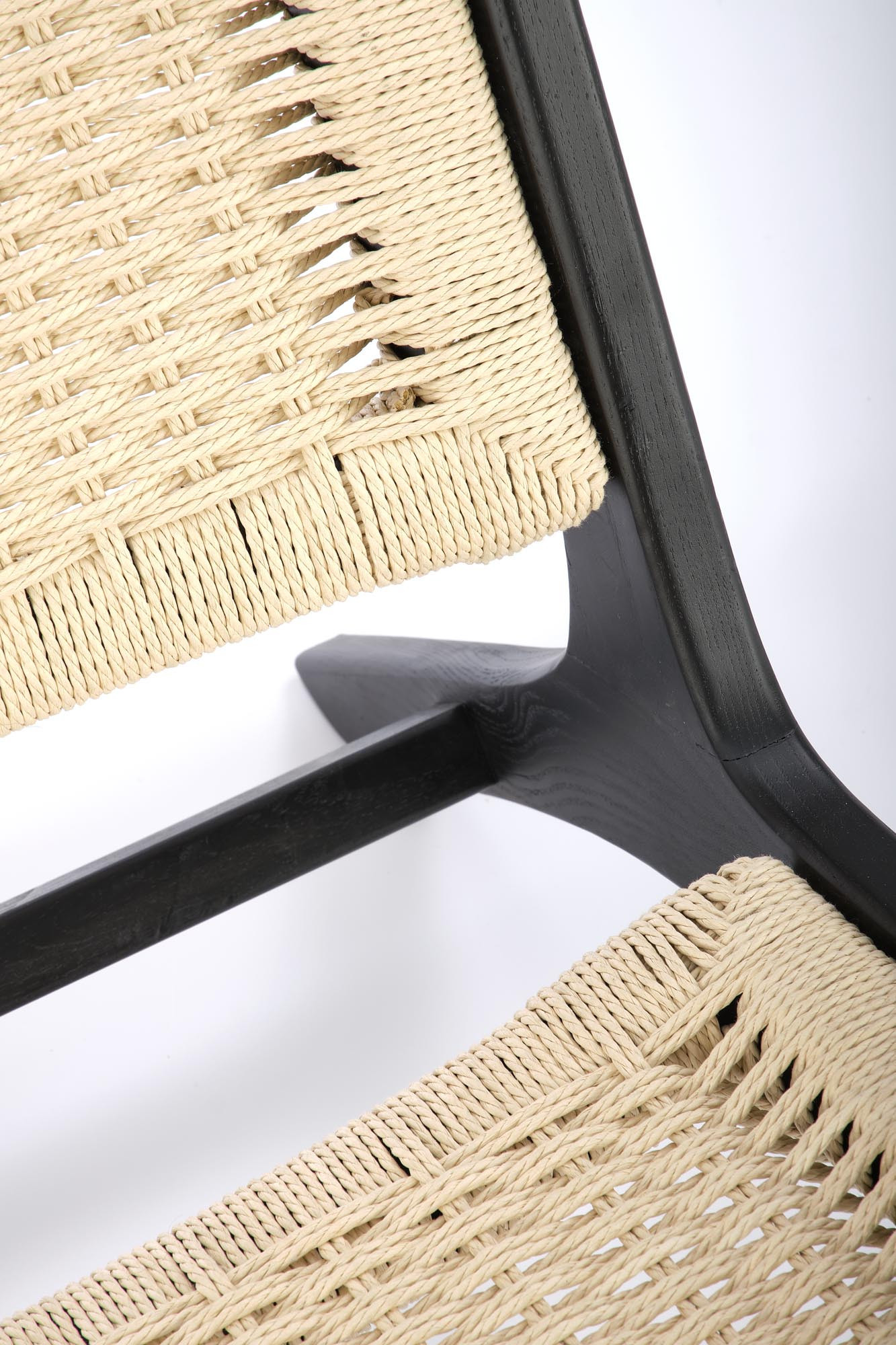 Zbliżenie na naturalne plecione siedzisko i czarną ramę fotela FODEN z litego drewna.