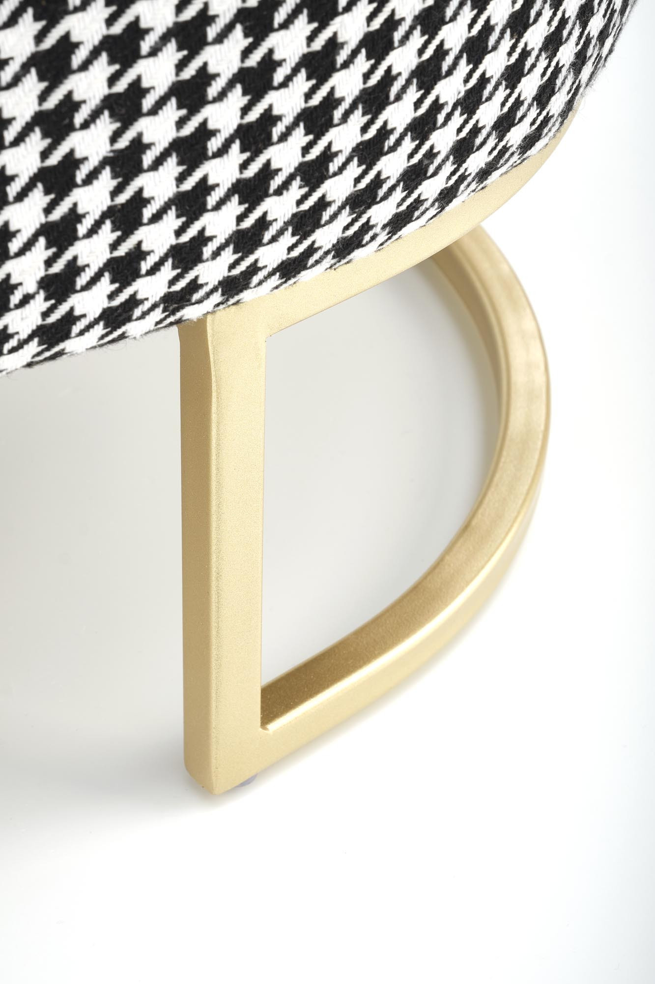 Zbliżenie na złotą nogę ławki HARMONY z czarno-białym wzorem pepitka.