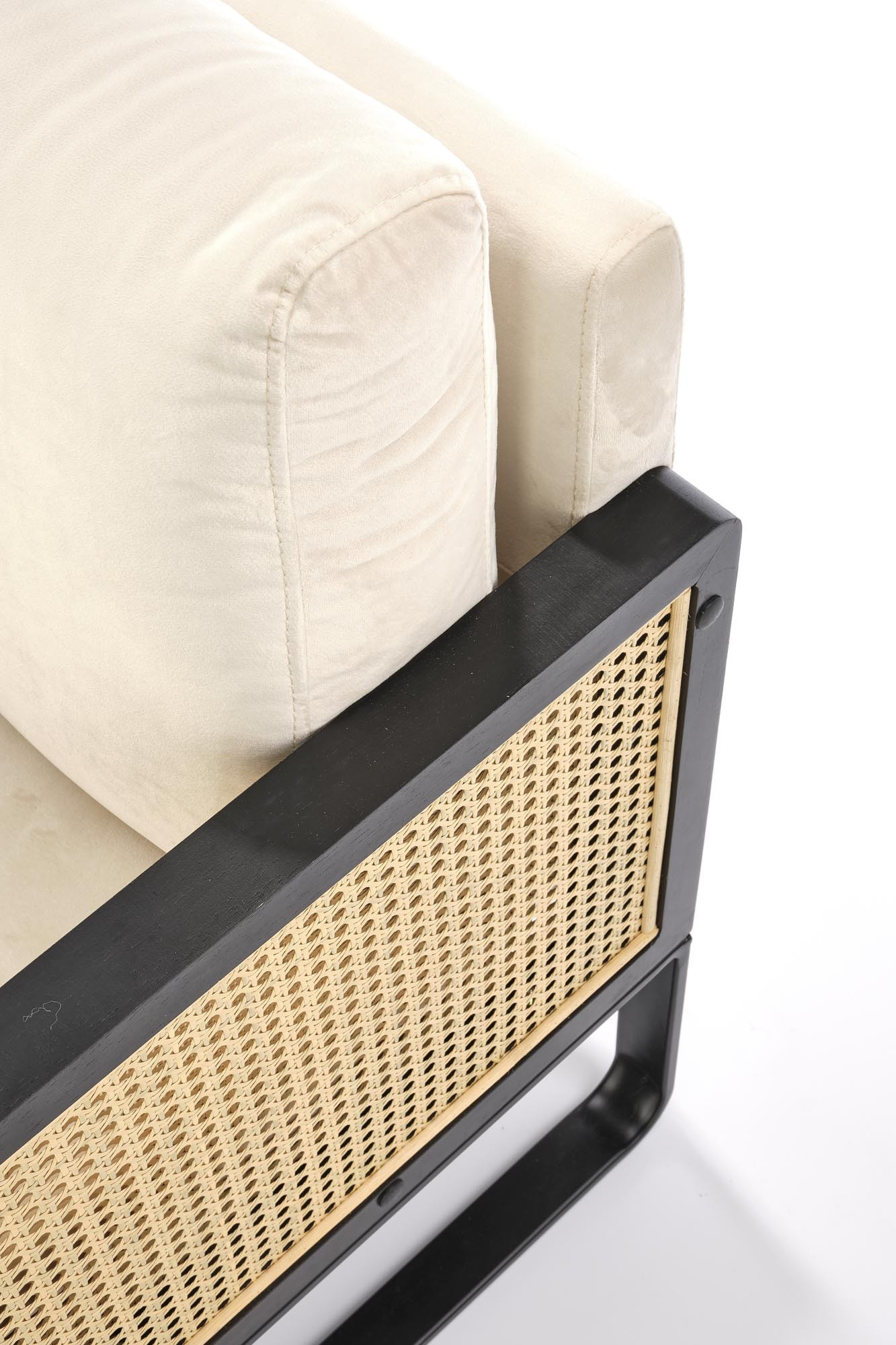 Zbliżenie na jasnobeżowe obicie i czarną ramę fotela ILARIO z plecionką rattanową.