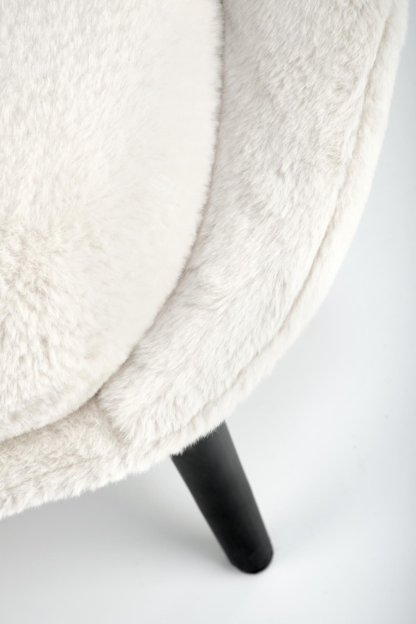 Zdjęcie detalu kremowego fotela MERRY Lapit 23 z miękkim obiciem i nogą w ciemnym kolorze.