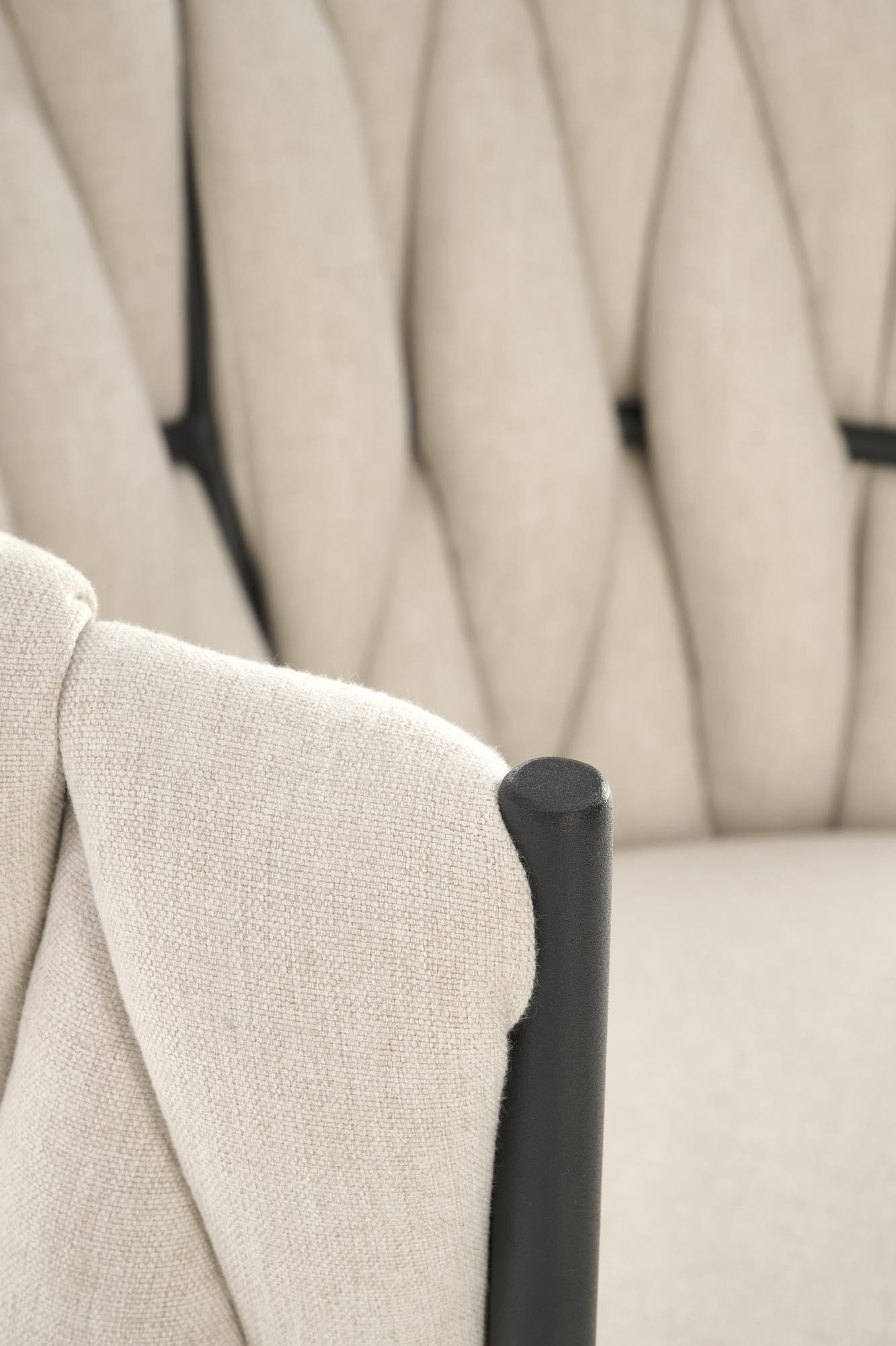 Zbliżenie na jasnobeżową tapicerkę fotela TALON z czarnymi metalowymi elementami.