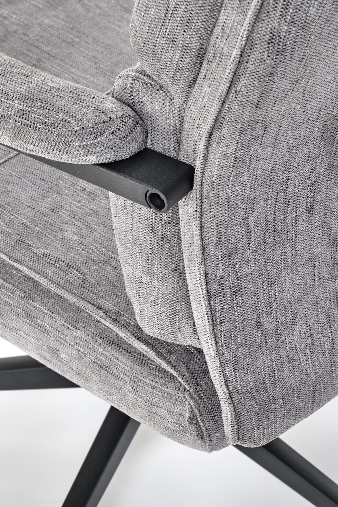 Zbliżenie na szarą tkaninę i czarną ramę podłokietnika fotela ADRIANO.