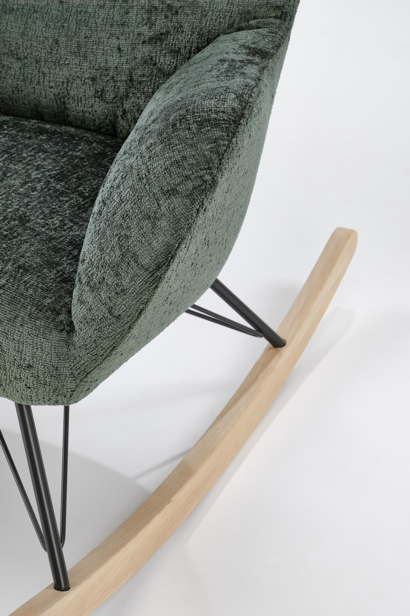 Zbliżenie na ciemnozielony fotel bujany CASTRO z litego drewna i stalowymi nogami.