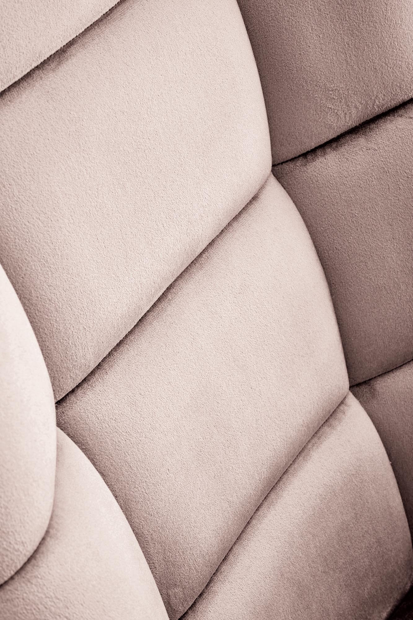 Zbliżenie na beżową, pikowaną tapicerkę fotela bujanego BAZALTO z velvetu.