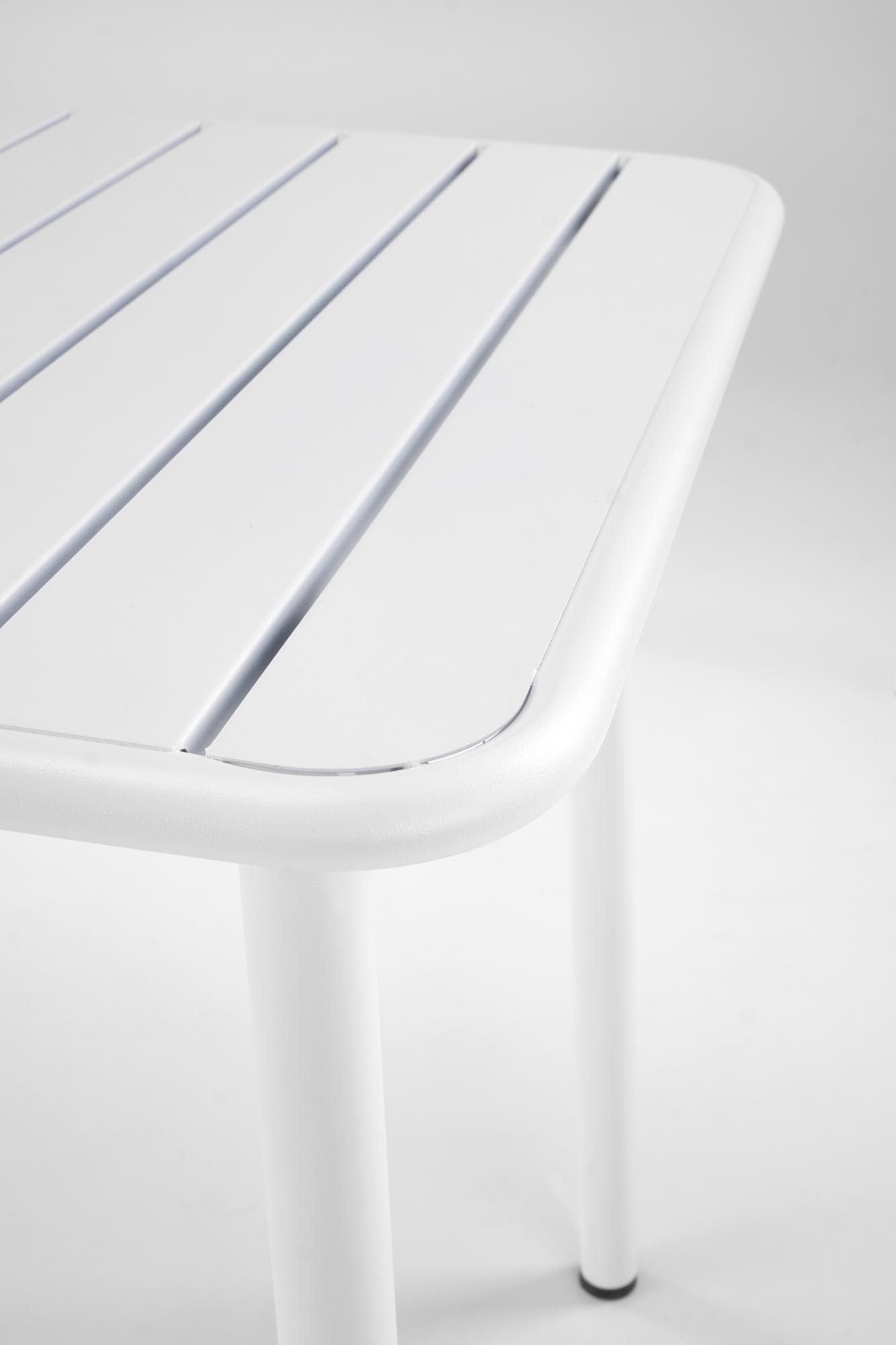 Zbliżenie na biały stół BOSCO z metalowymi nogami i prostokątnym blatem z listew.