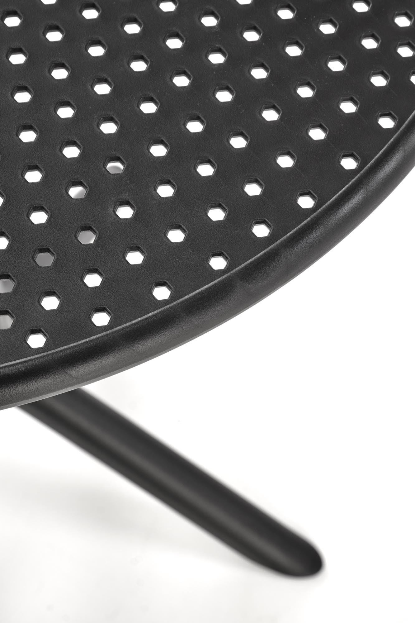 Zbliżenie na perforowany blat okrągłego stołu CALVO z czarnego polipropylenu.