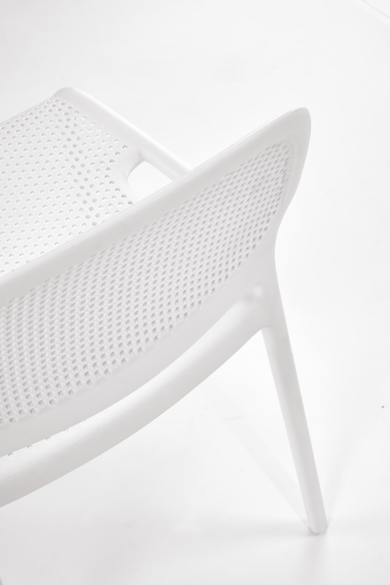 Zbliżenie na perforowane oparcie białego krzesła K532 z polipropylenu.
