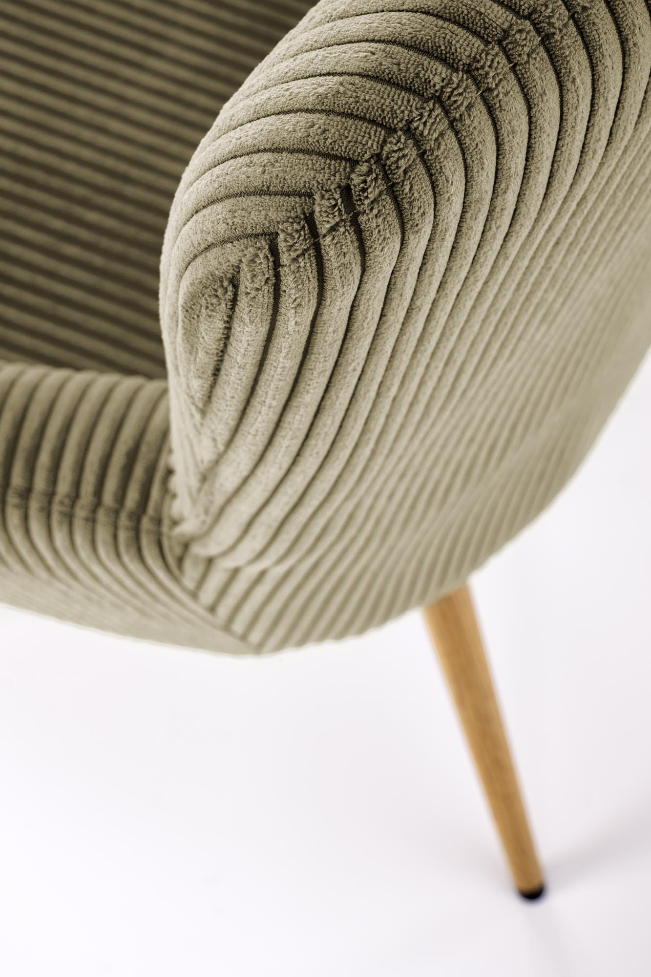 Zbliżenie na oliwkowy fotel wypoczynkowy AMARO z tkaniny sztruksowej i drewnianymi nogami.