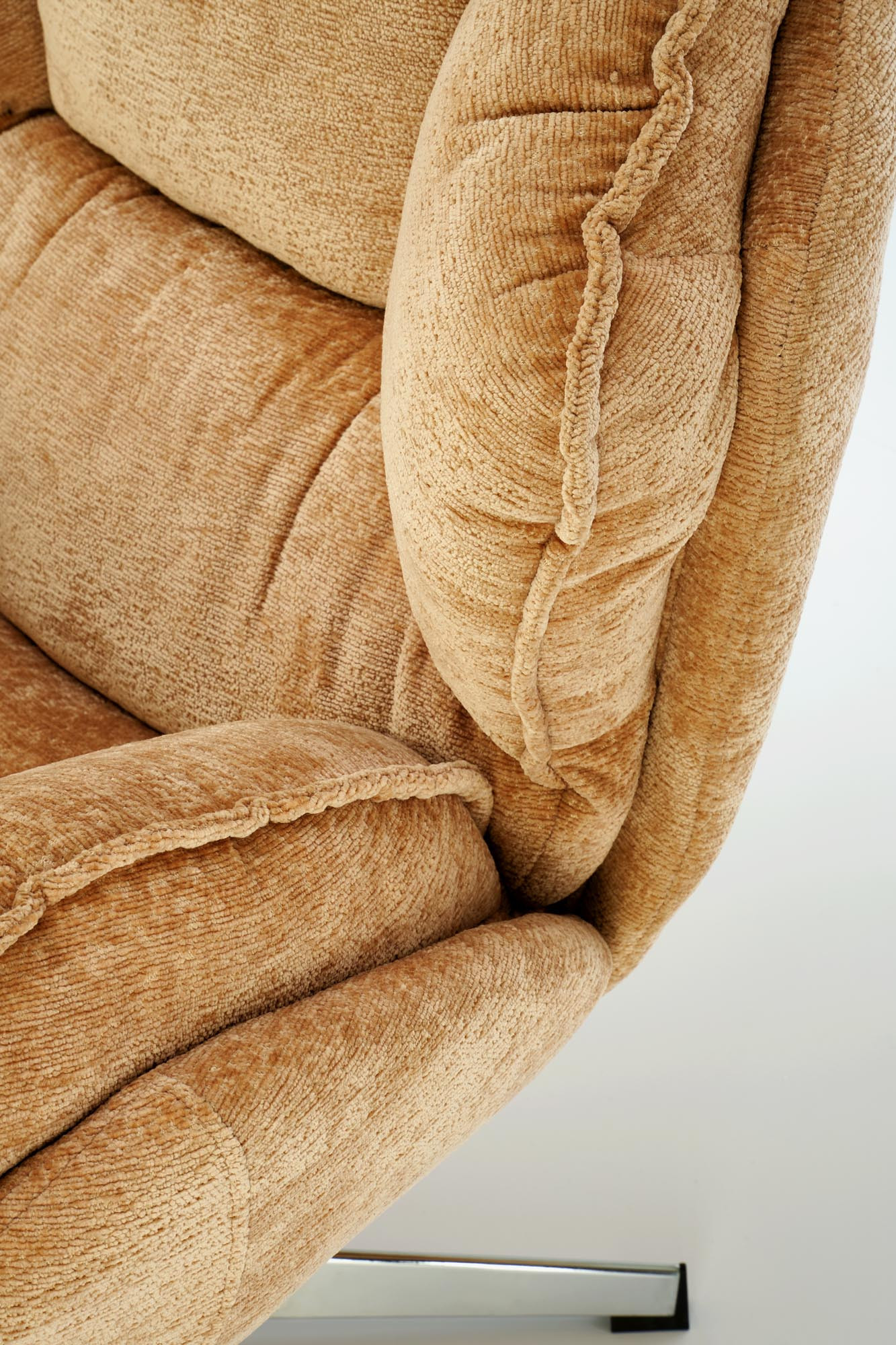 Zbliżenie na musztardowy fotel wypoczynkowy GUIDO z chromowanymi nogami i miękkim obiciem.