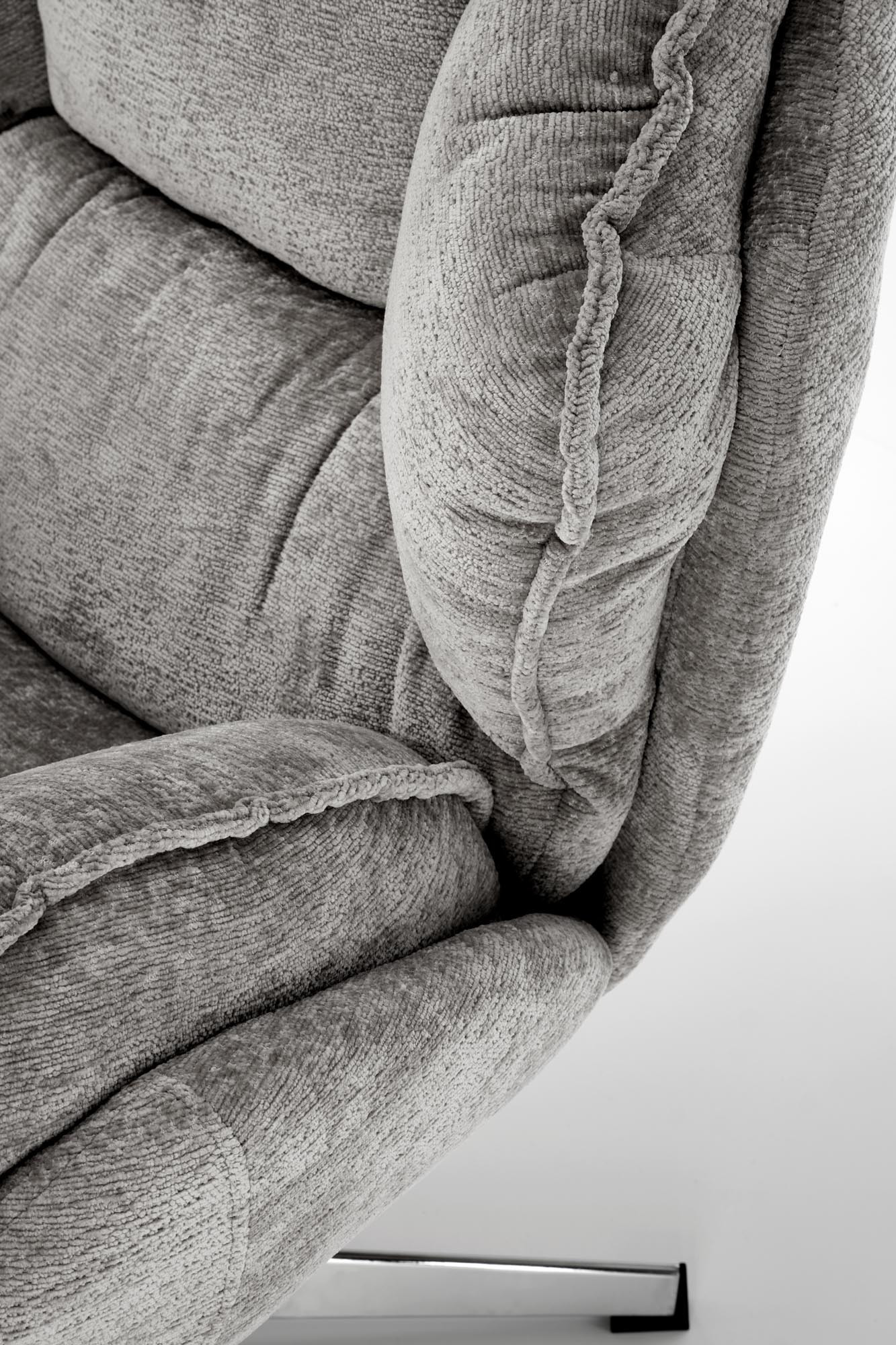 Zbliżenie na szarą tapicerkę fotela GUIDO z chromowaną podstawą.