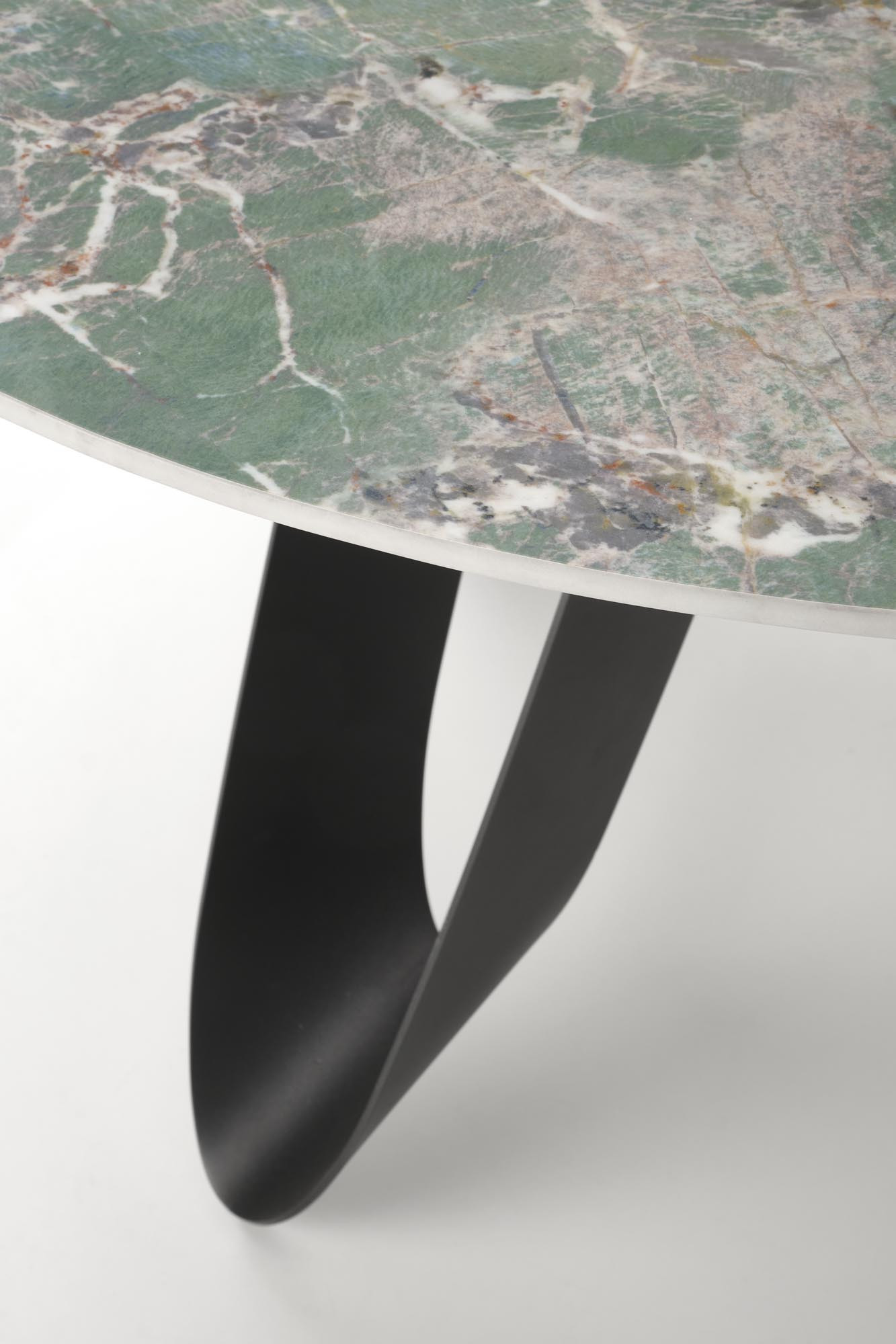 Zbliżenie na zielony marmurowy blat i czarne stalowe nogi okrągłego stołu GIOVANI.