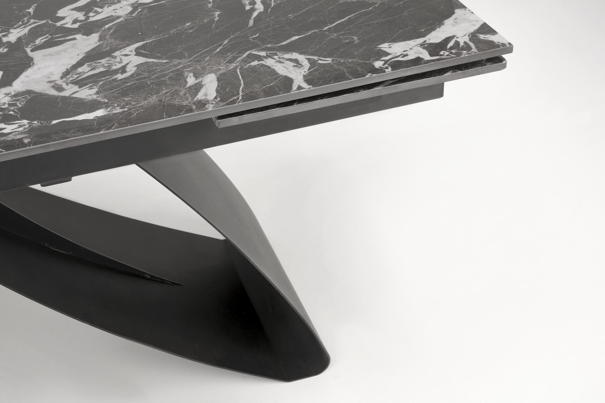 Zbliżenie na czarny marmurowy blat stołu HILARIO z geometrycznymi, czarnymi nogami.