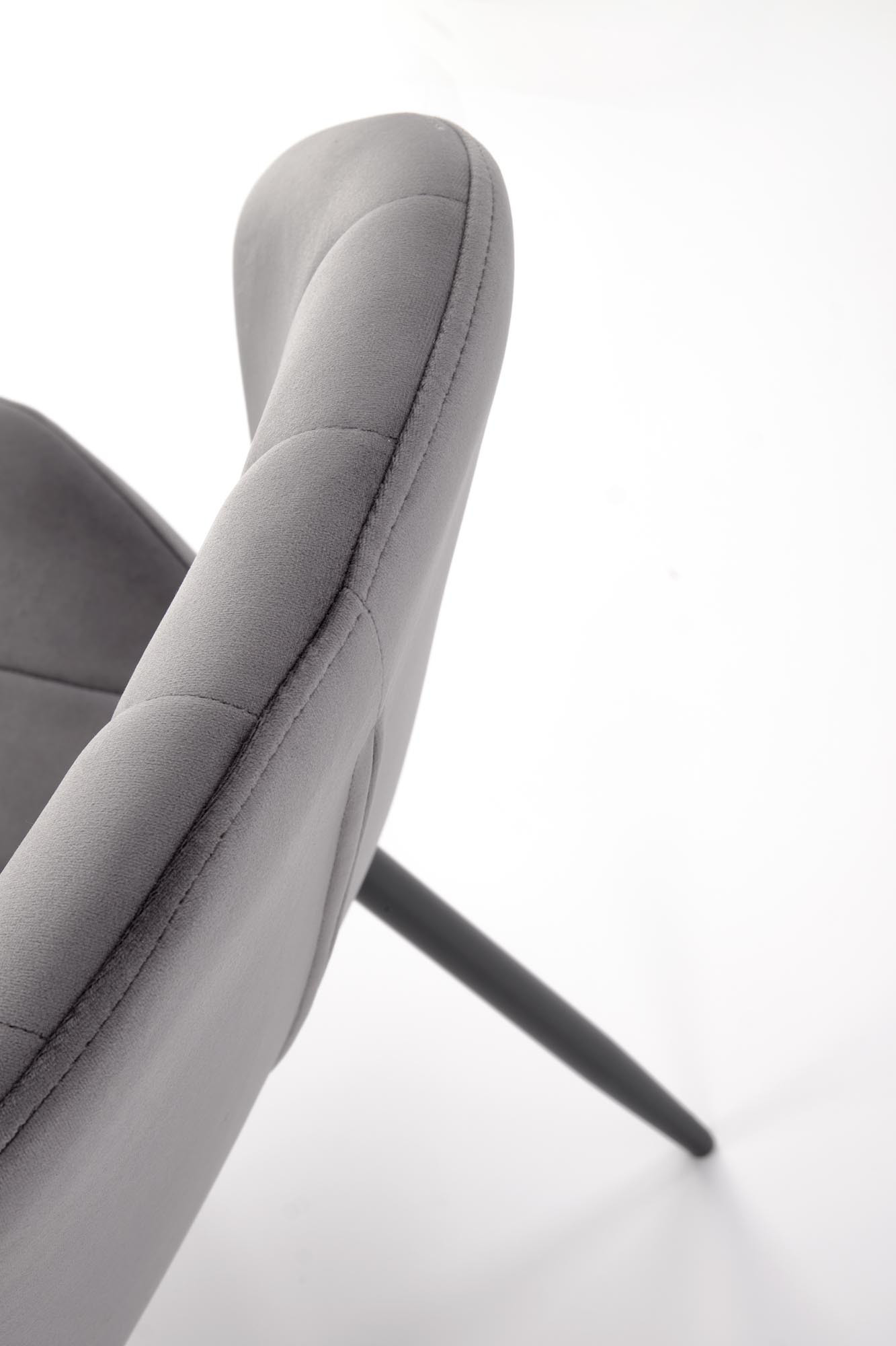 Zbliżenie na pikowane oparcie musztardowego krzesła K538 z weluru na stalowych nogach.