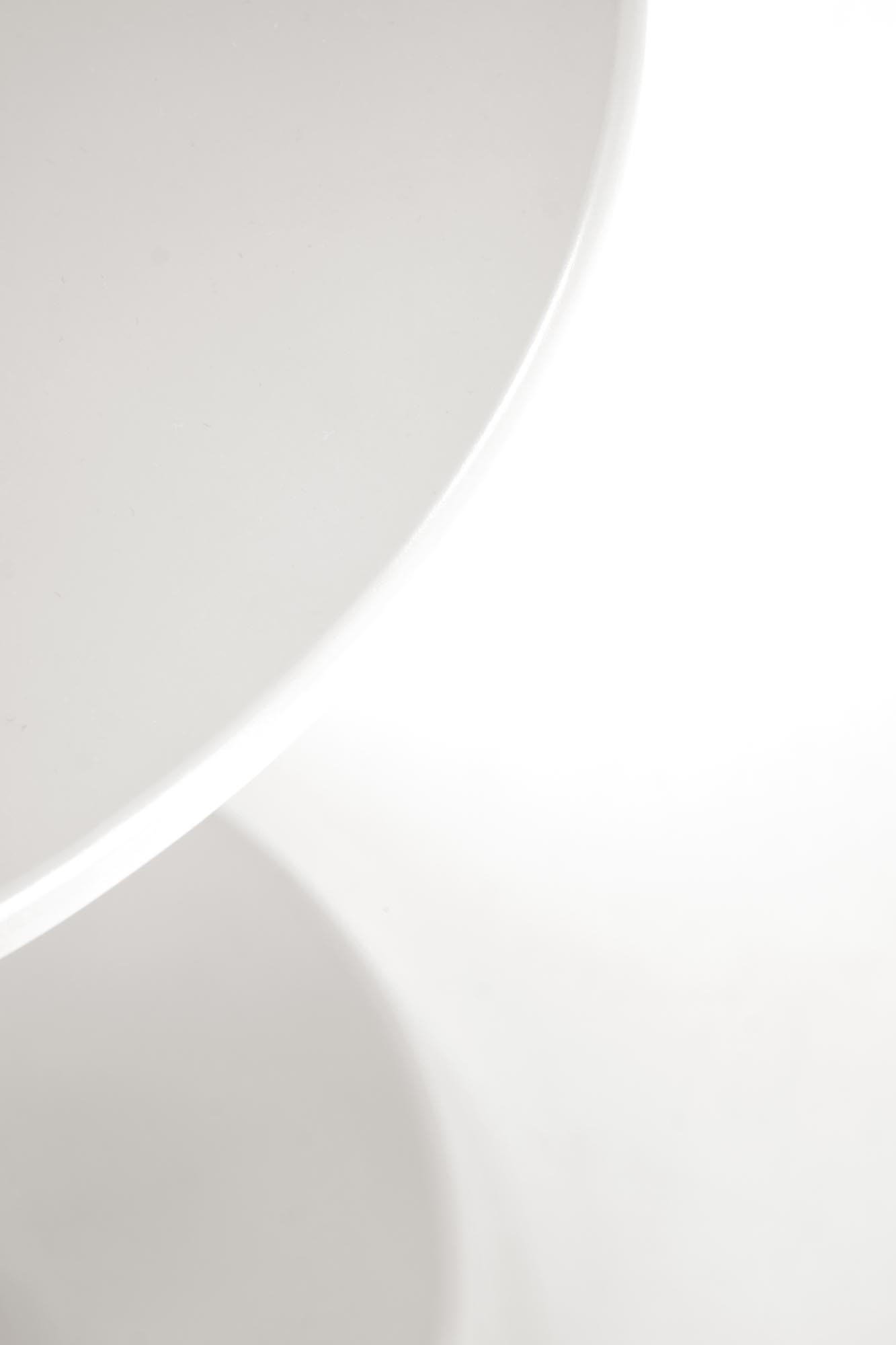 Zbliżenie na biały blat okrągłej ławy CIRILLA z lakierowanego MDF i litego drewna.