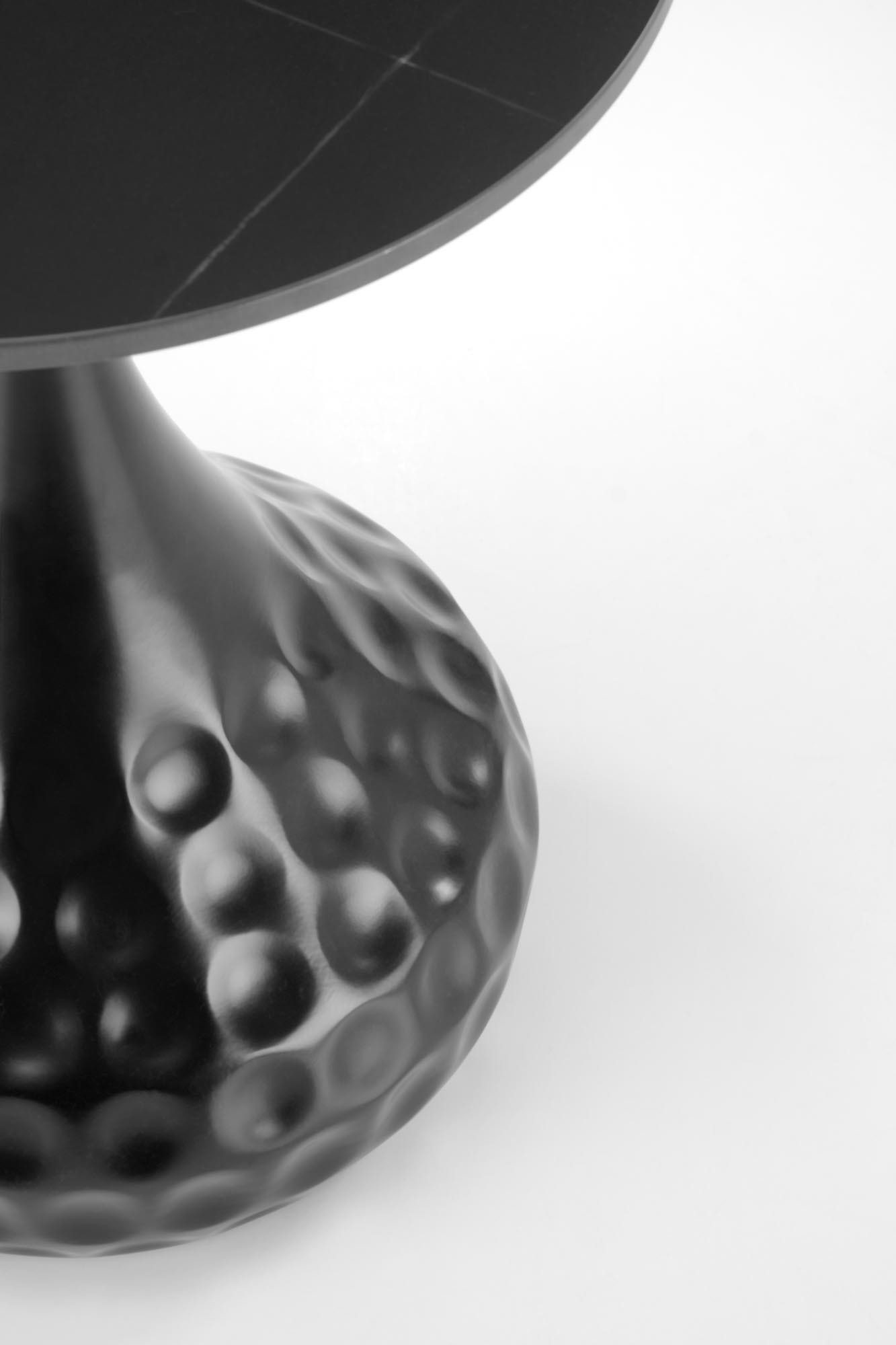 Zbliżenie na czarny marmurowy stolik VERDE z designerską podstawą w kształcie kielicha.