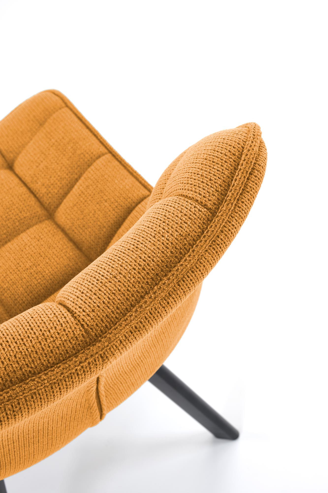 Zbliżenie na pikowaną tapicerkę musztardowego krzesła K549 z czarnymi stalowymi nogami.