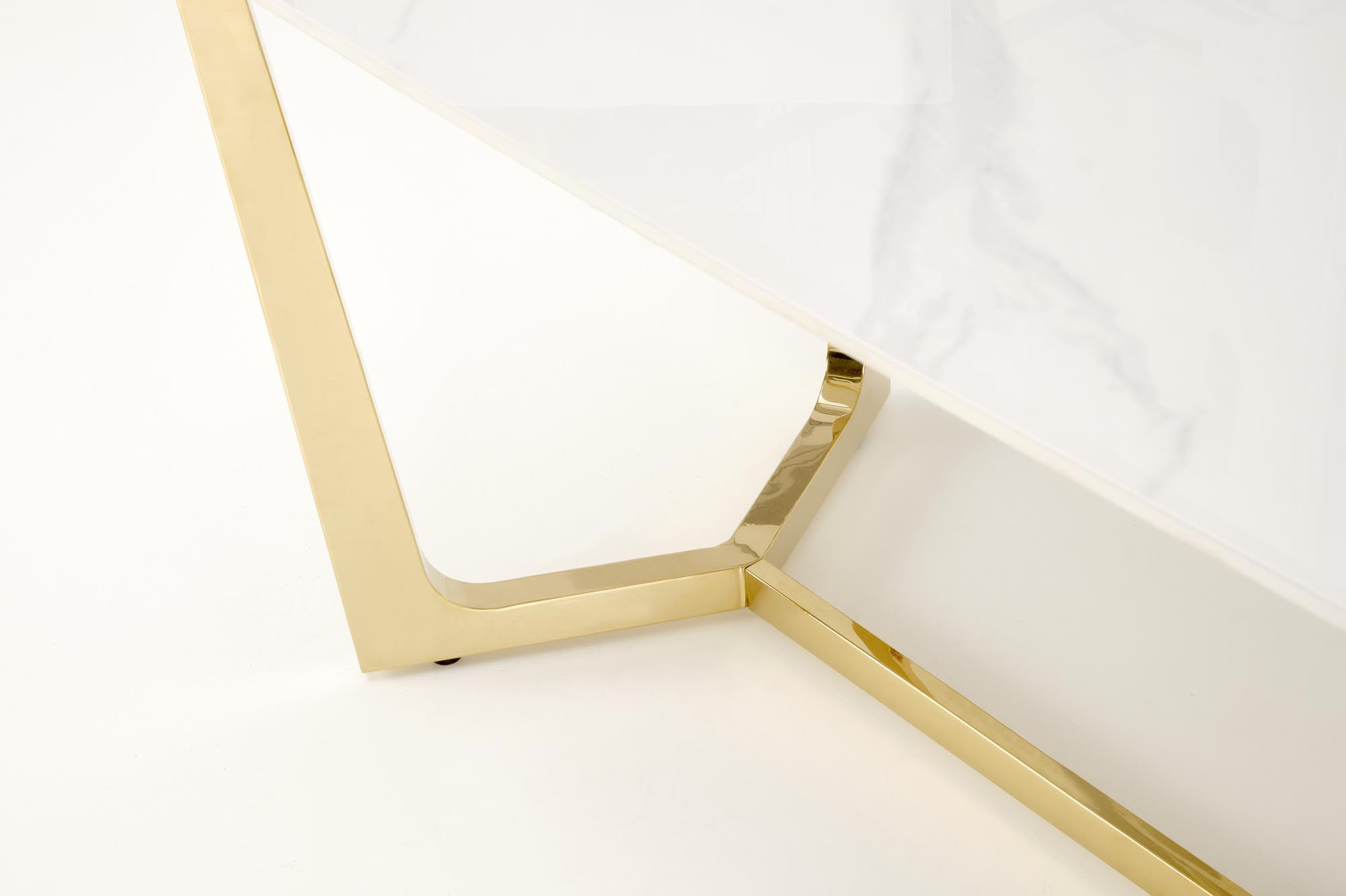 Zbliżenie na złote, eleganckie nogi stołu glamour z białym blatem imitującym marmur.