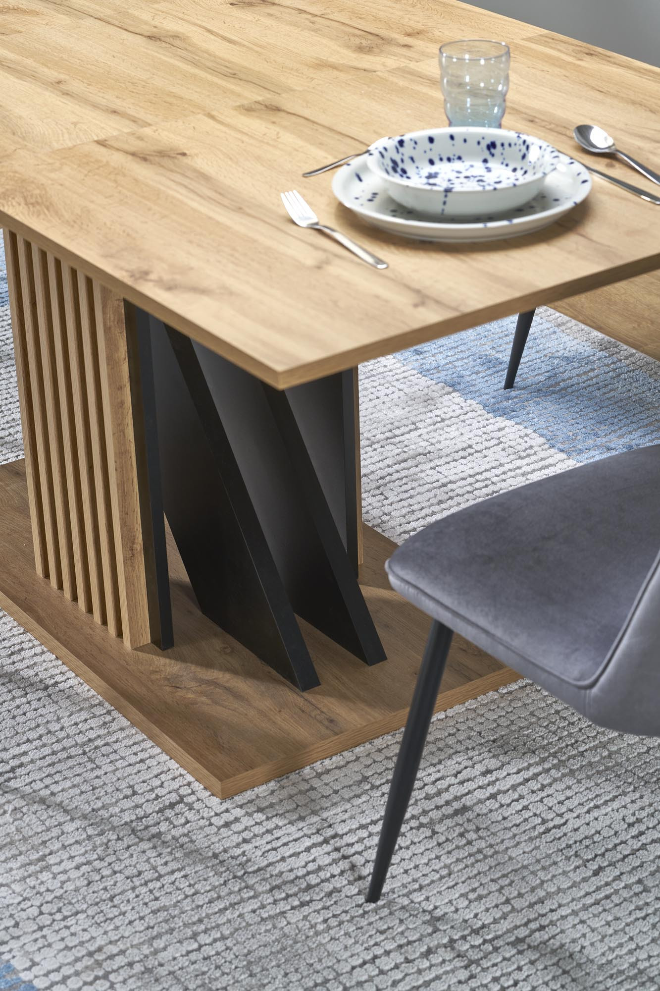 Zbliżenie na podstawę rozkładanego stołu FABIANO z dębu wotan i czarnymi elementami.