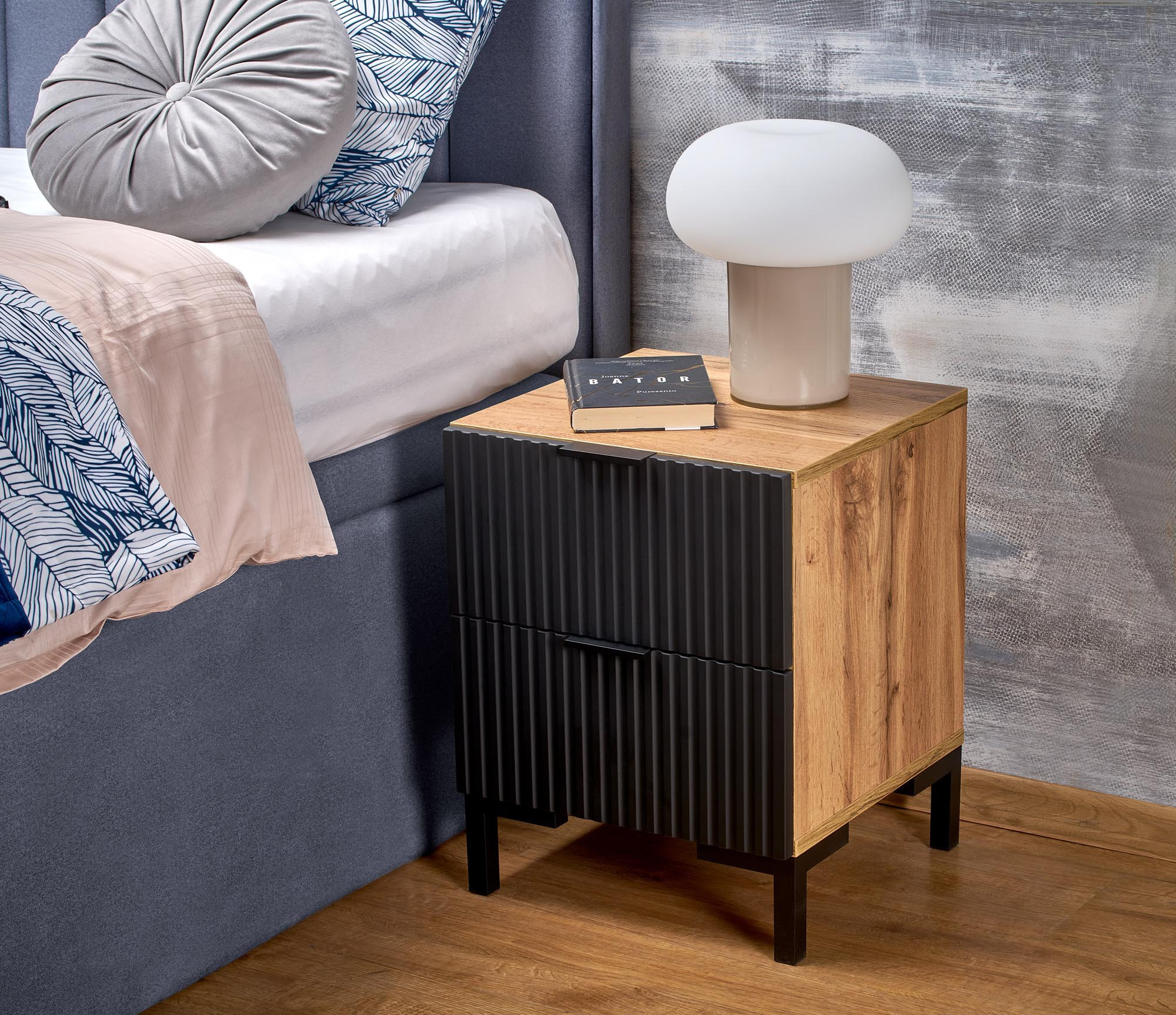 Szafka nocna z dębu craft i czarnego drewna, widok z przodu, z lampką i książką na blacie.