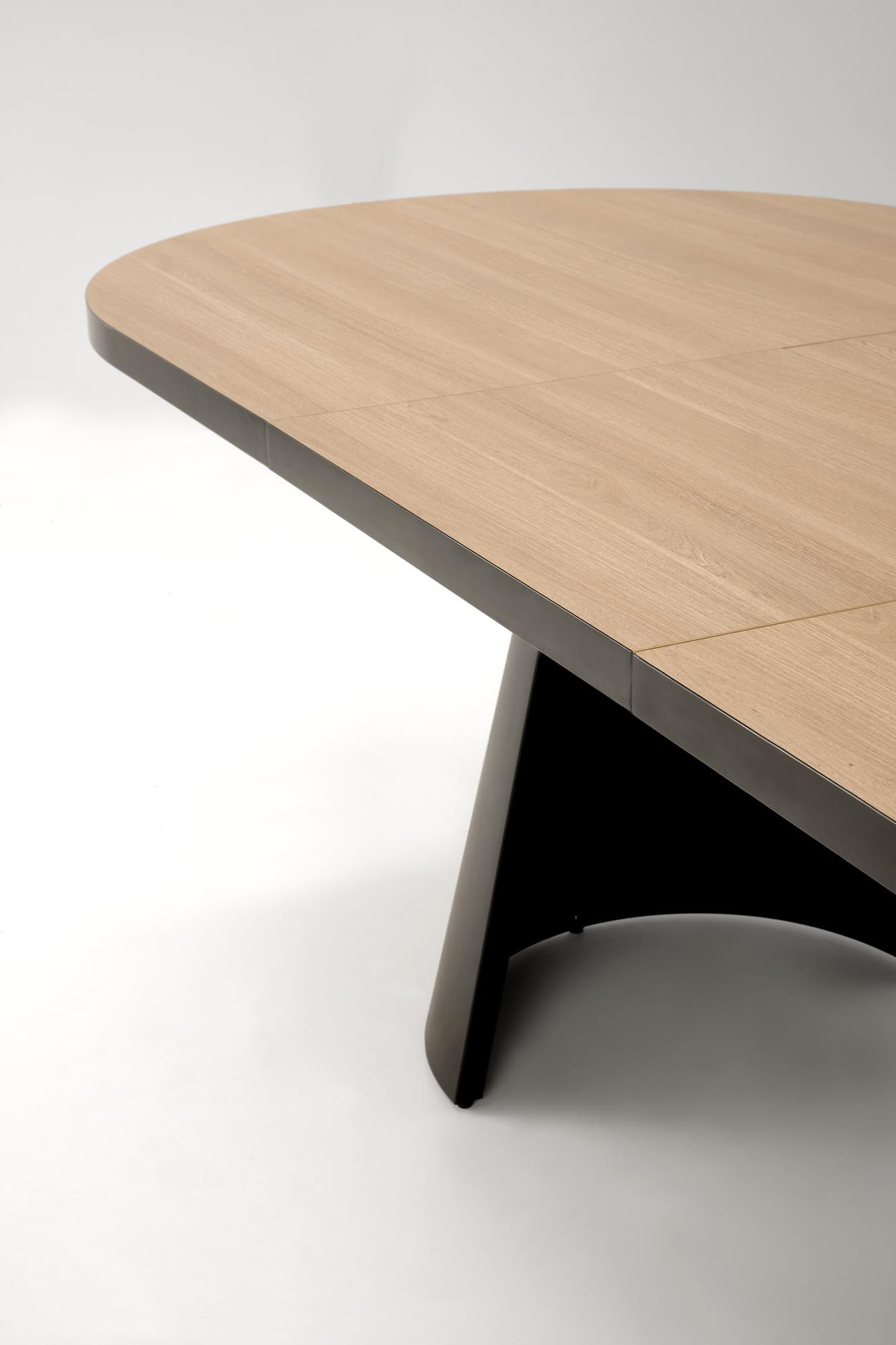 Zbliżenie na blat owalnego stołu GIACOMO z rozkładanym blatem na dwóch kolumnowych nogach.