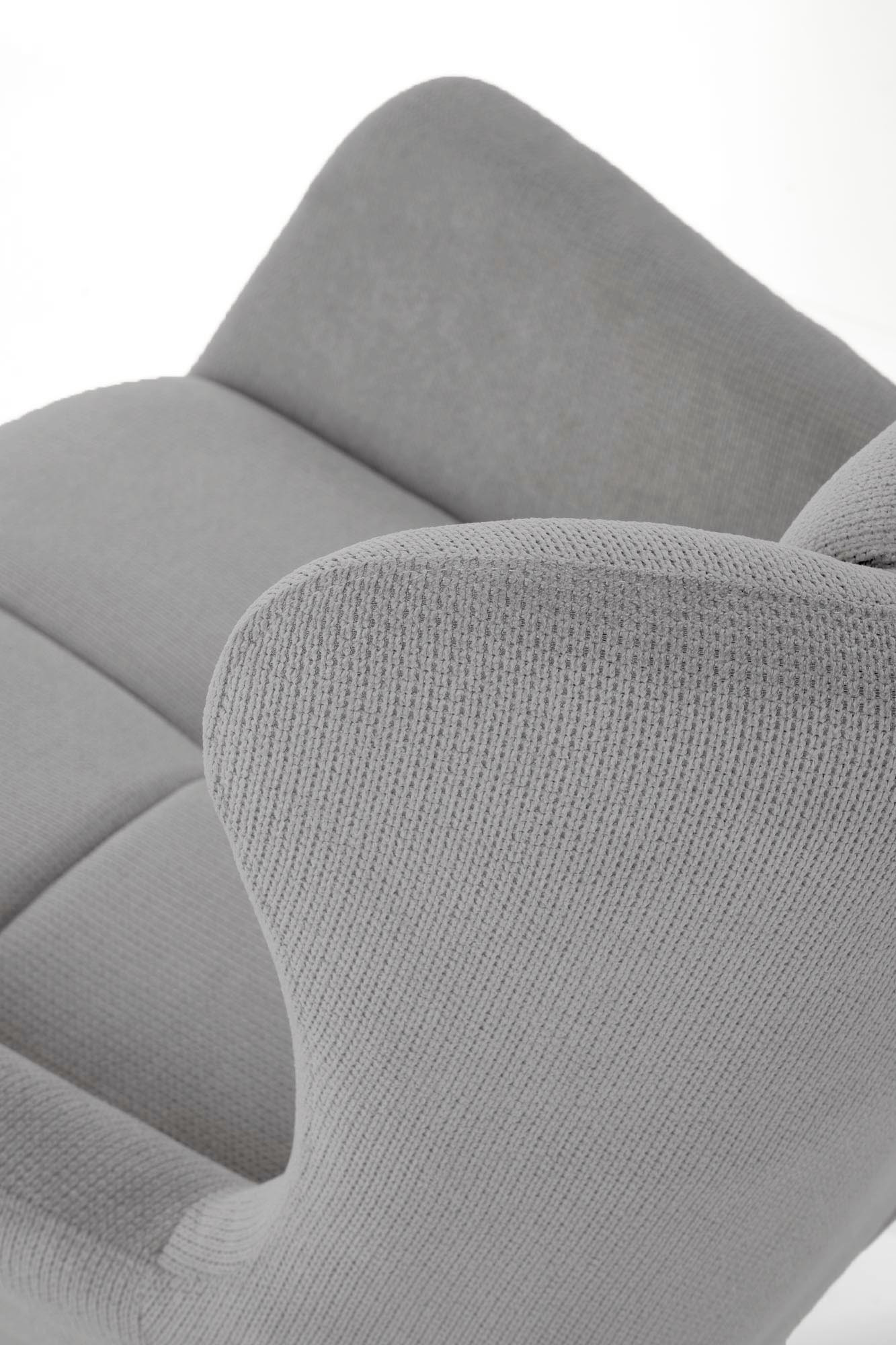 Zbliżenie na popielaty fotel wypoczynkowy BYRON uszak z pikowanym oparciem i stalowymi nogami.