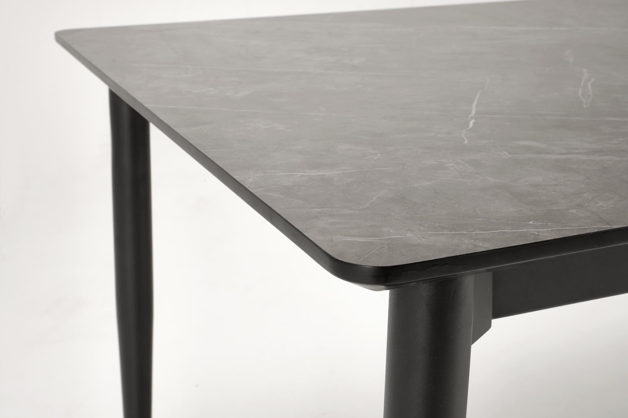 Zbliżenie na blat  w kolorze popielatego marmuru i czarne stalowe nogi rozkładanego stołu CHARLES.