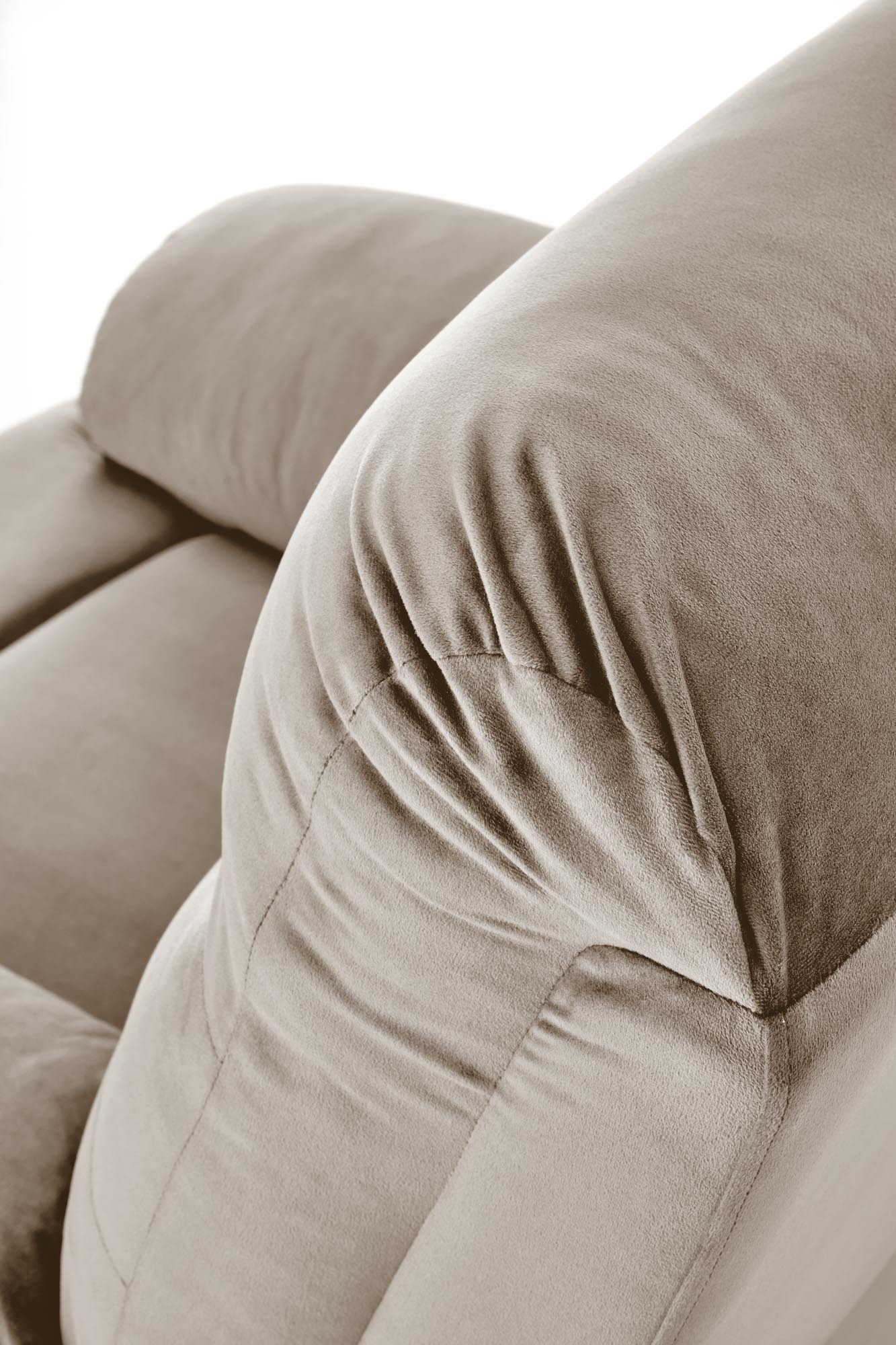Zbliżenie na beżowy fotel wypoczynkowy DRAGER z miękkim, welurowym obiciem.