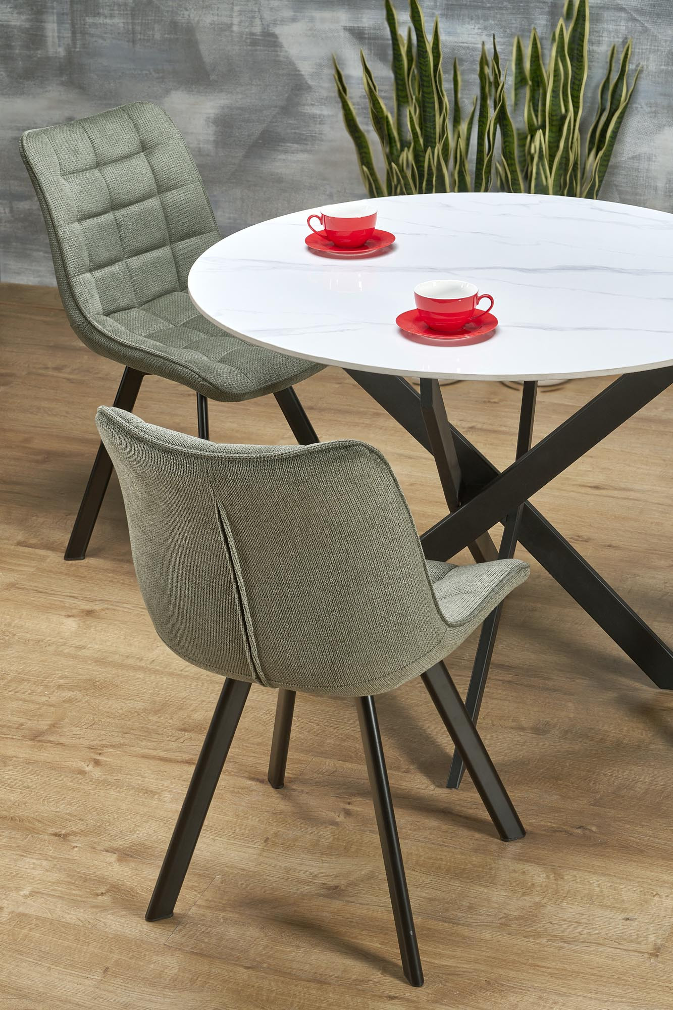 Okrągły stół z białym marmurowym blatem i czarną krzyżową podstawą, nowoczesny minimalizm.