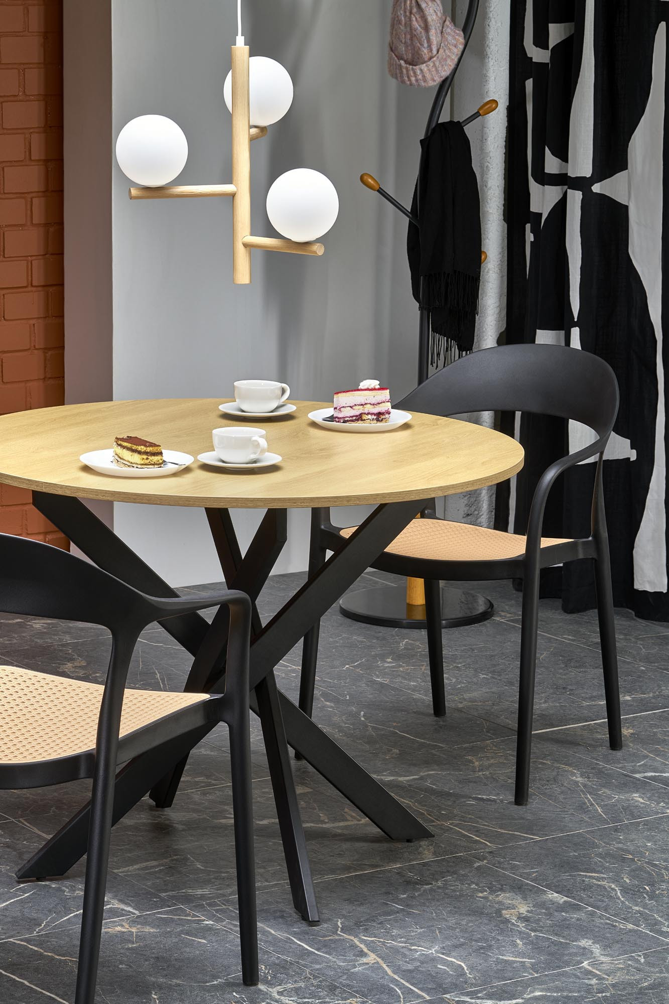Okrągły stół EDGAR z dębu złotego na czarnej stalowej podstawie – widok z przodu, z dwoma krzesłami.