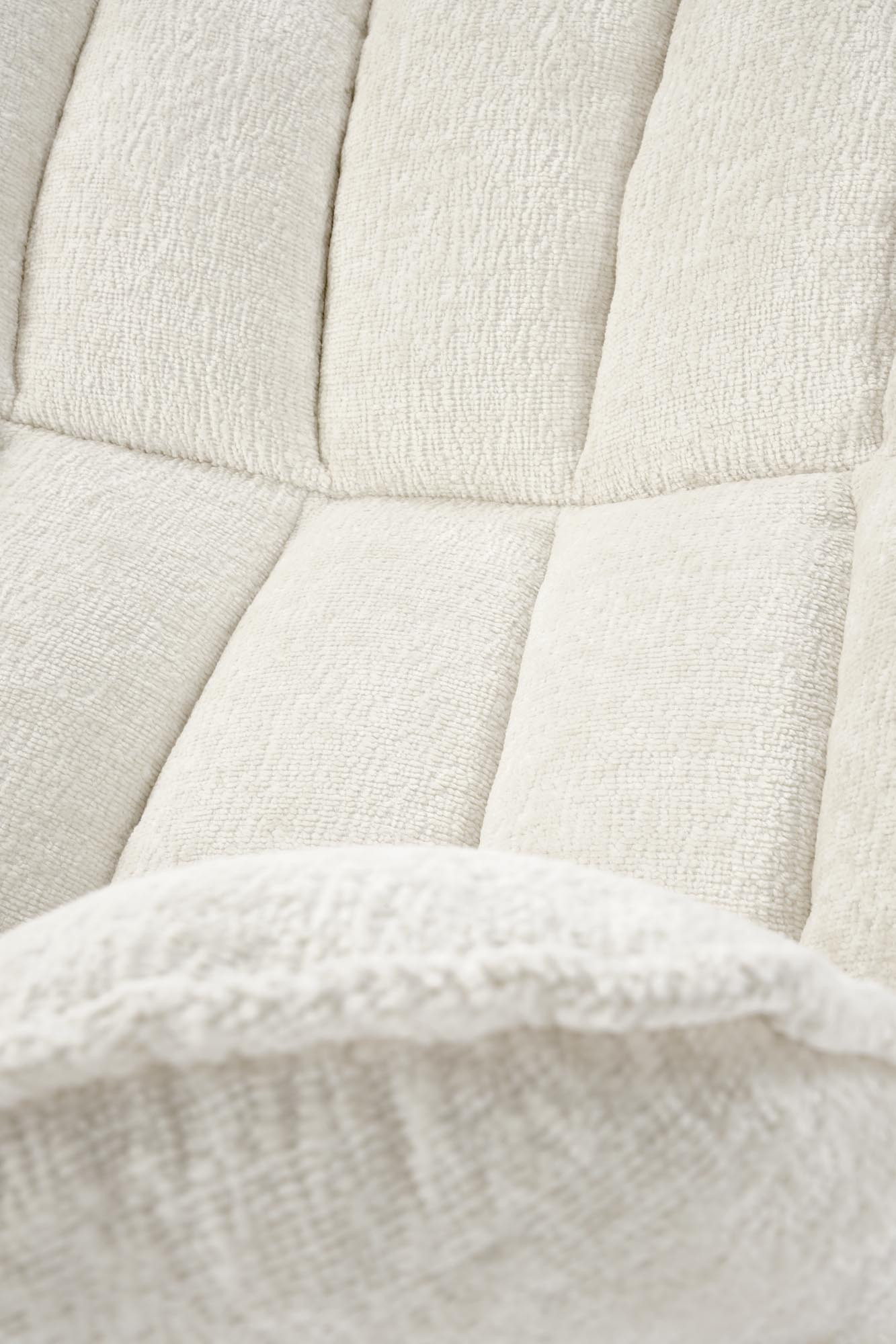 Zbliżenie na pikowaną tkaninę kremowego fotela wypoczynkowego FOFANA.